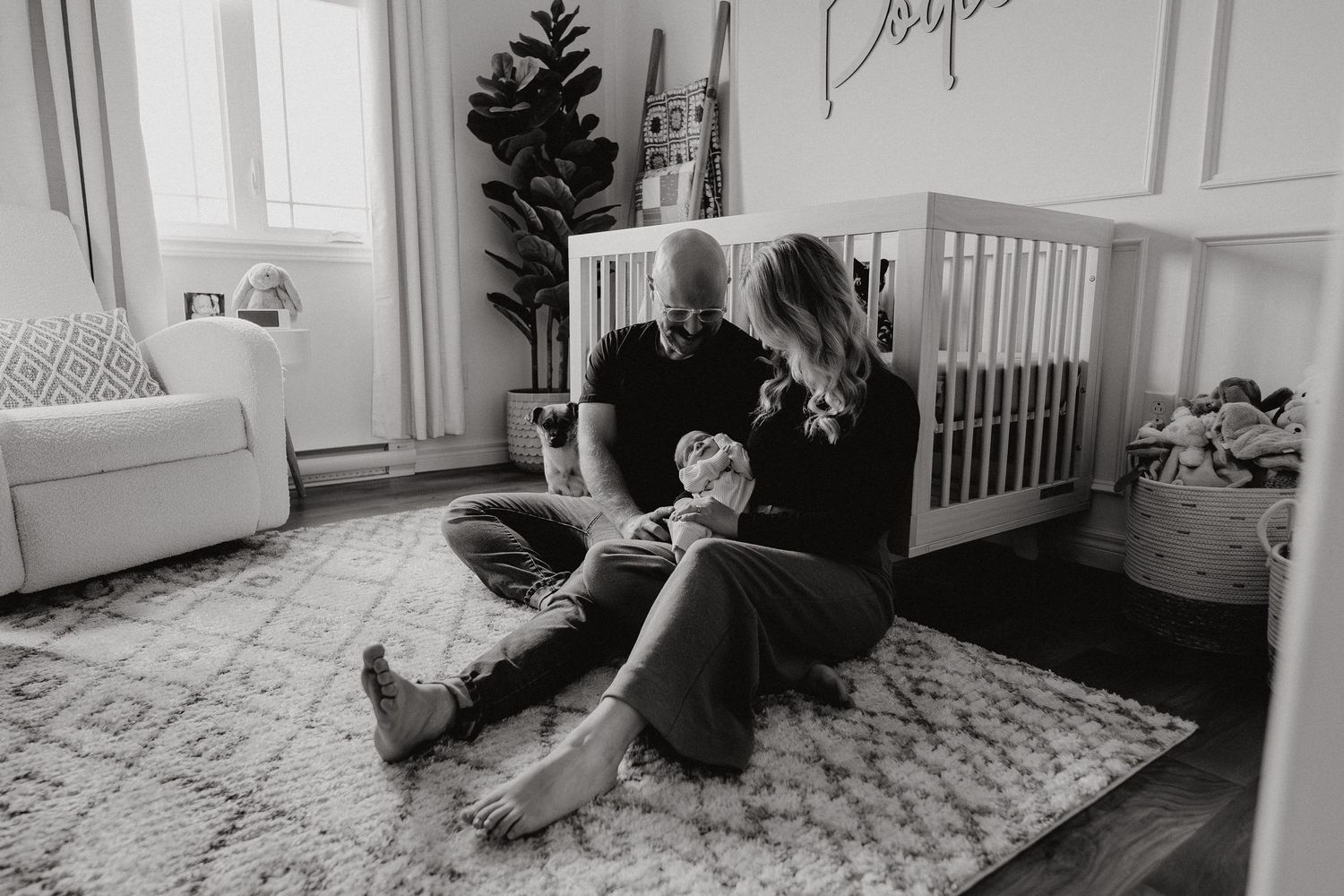 Black and white photo showing adults sitting on nursery room floor.