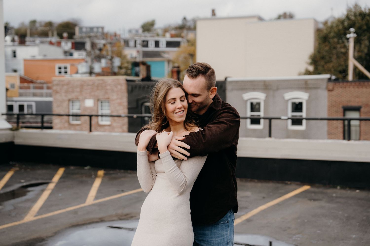 Black and white portrait of couple's intimate moment against city rooftop setting.