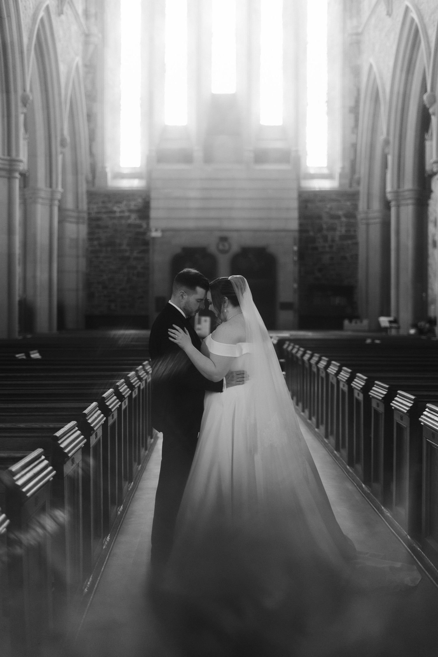 Ethereal wedding moment captured in dreamy cathedral light with gothic stone columns.