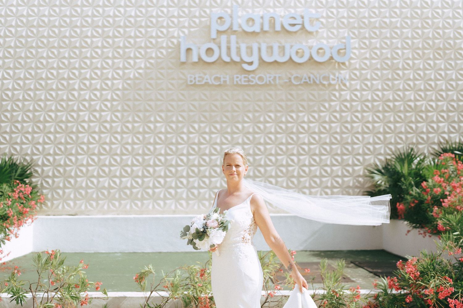 Bride and groom taking romantic photos against a modern white textured wall.