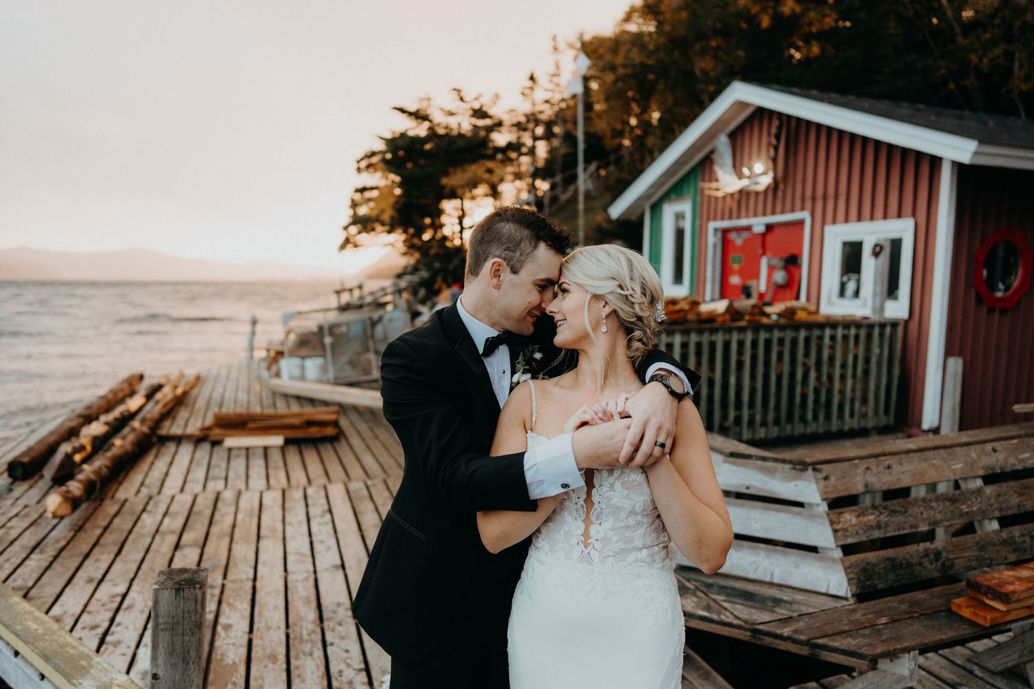 Romantic golden hour wedding photography on rustic wooden deck by the water.