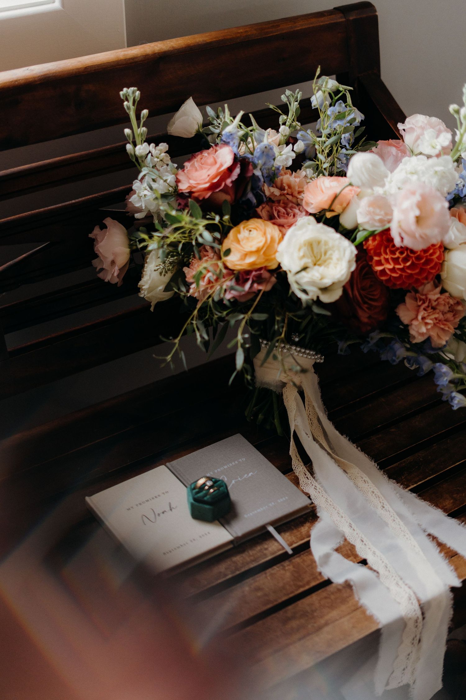 Wedding details featuring floral arrangements and stationery on wooden church pews.