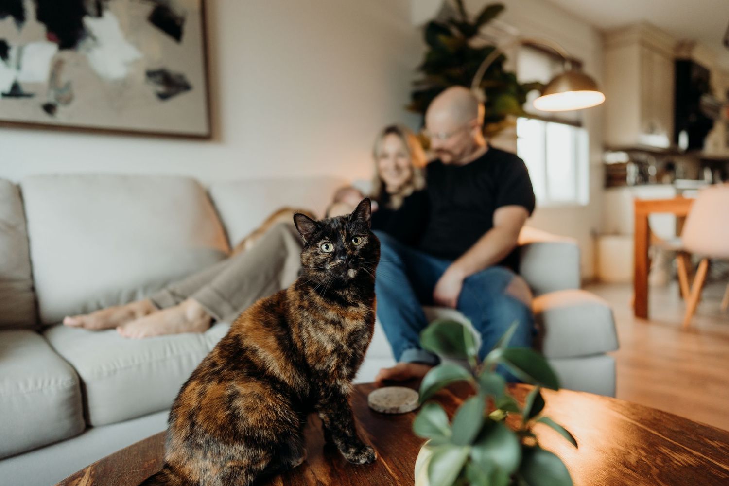 A family sits together on a comfortable sofa while their dog rests nearby.