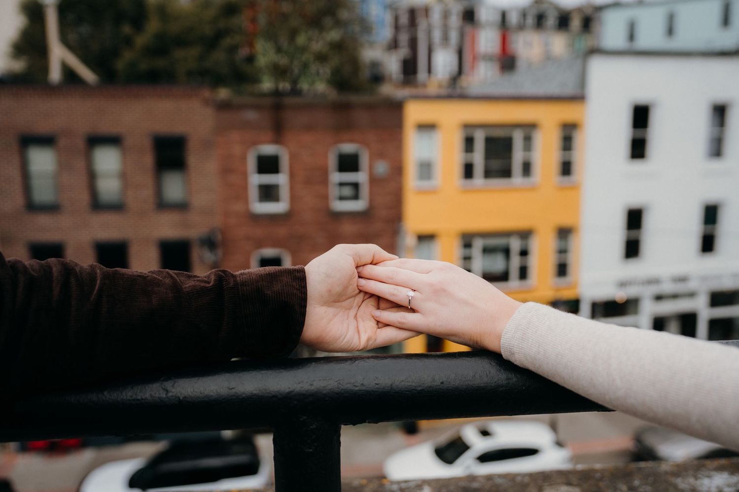 Hands reaching towards each other with city buildings visible in the background.