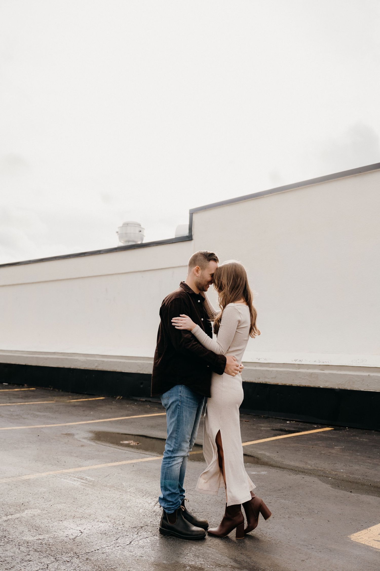 A romantic embrace between a couple in a modern urban setting with clean architectural lines.