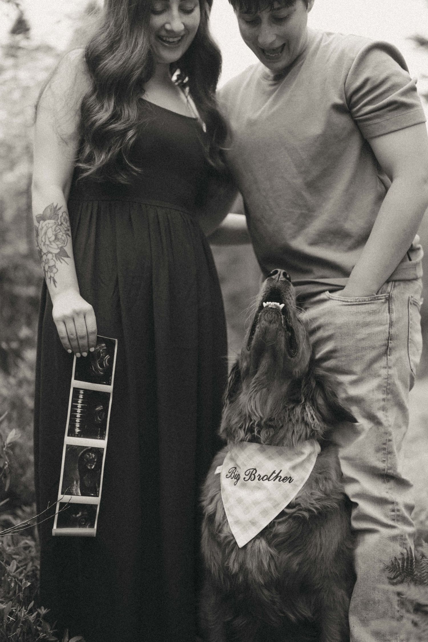 Black and white pregnancy announcement photo with couple holding ultrasound, dog wearing Big Brother bandana.