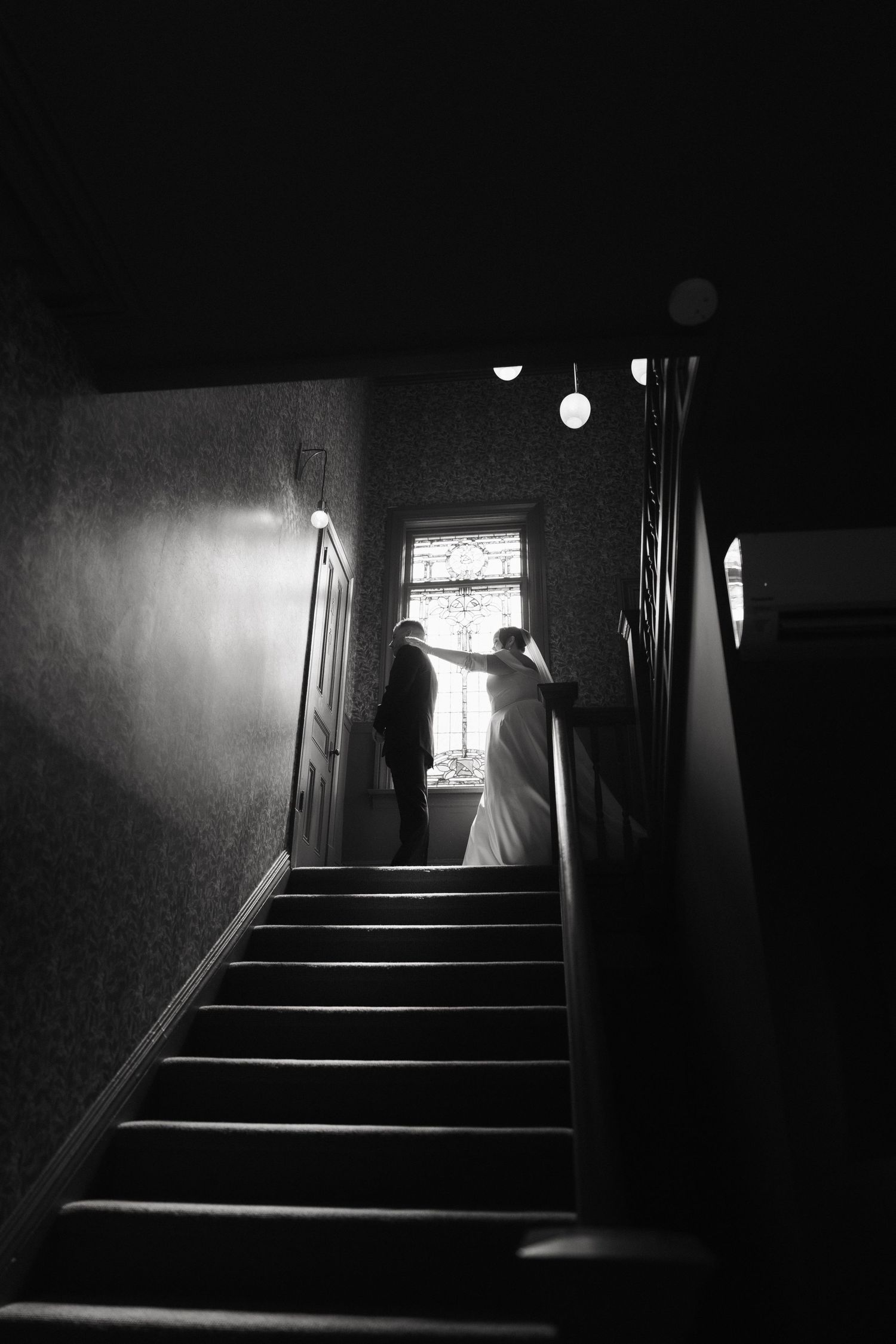 Dark staircase with dramatic shadows and light streaming through window.