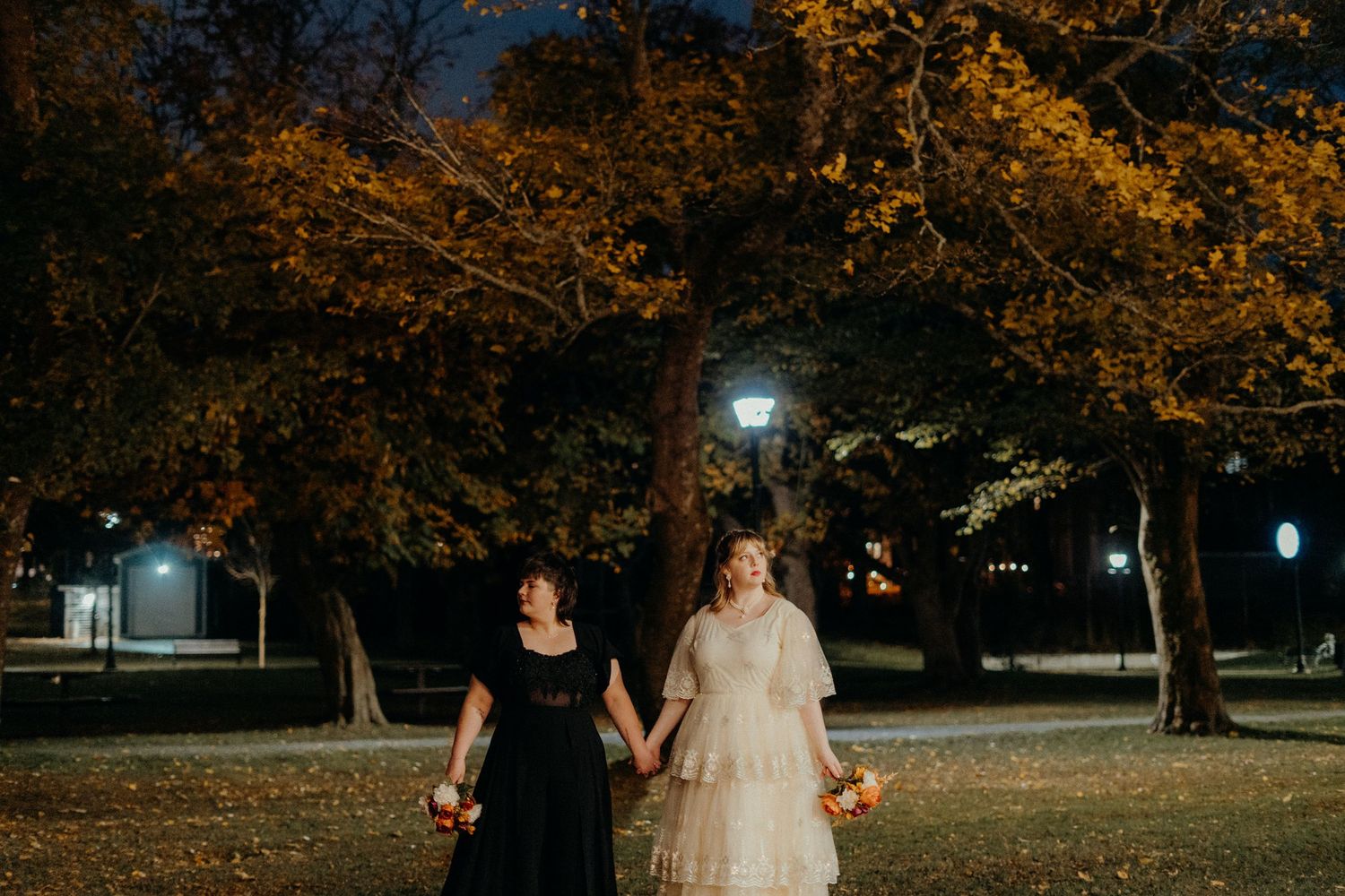 Romantic evening wedding portrait under illuminated autumn trees.