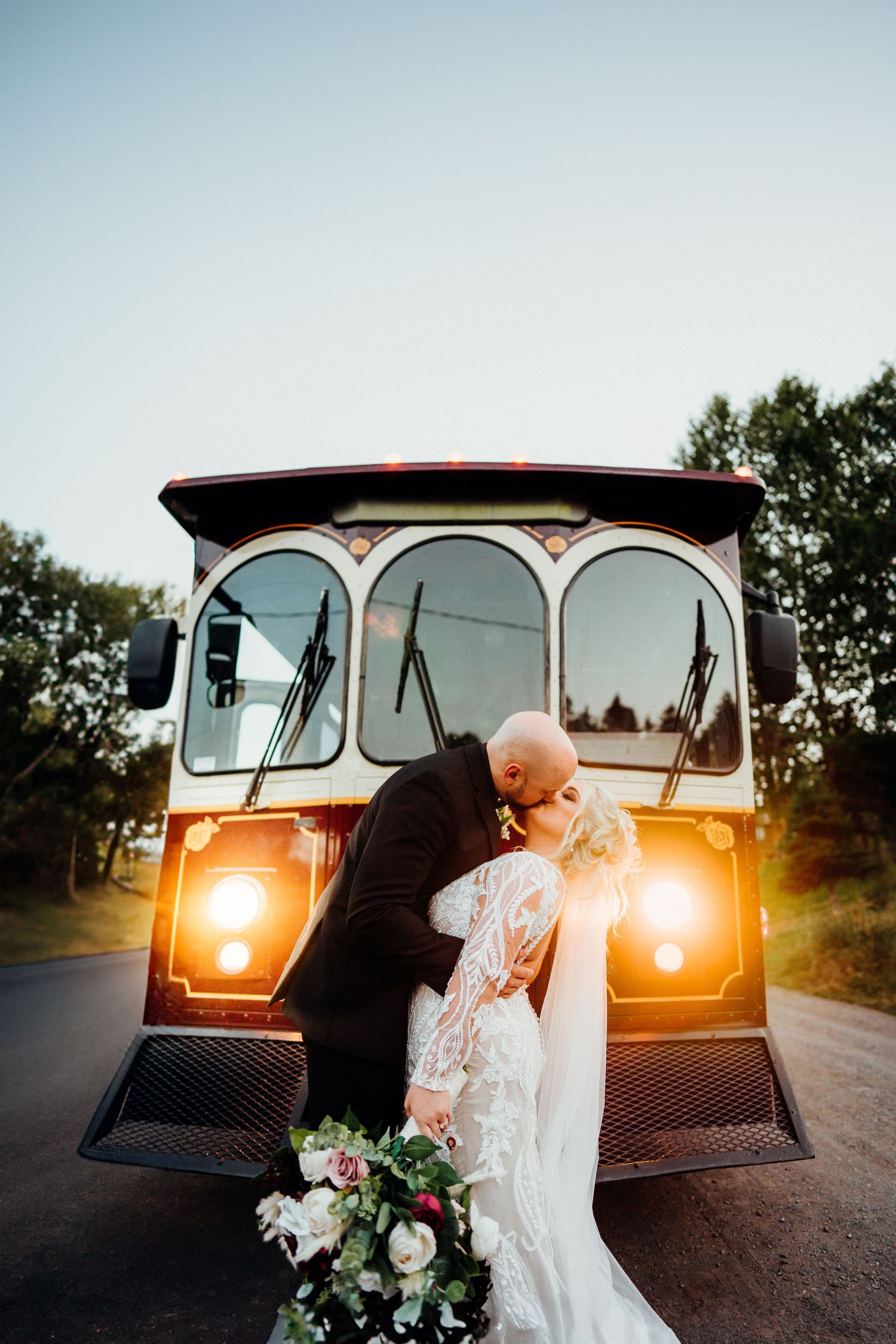 Vintage car wedding photos with glowing headlights at dusk featuring classic styling.