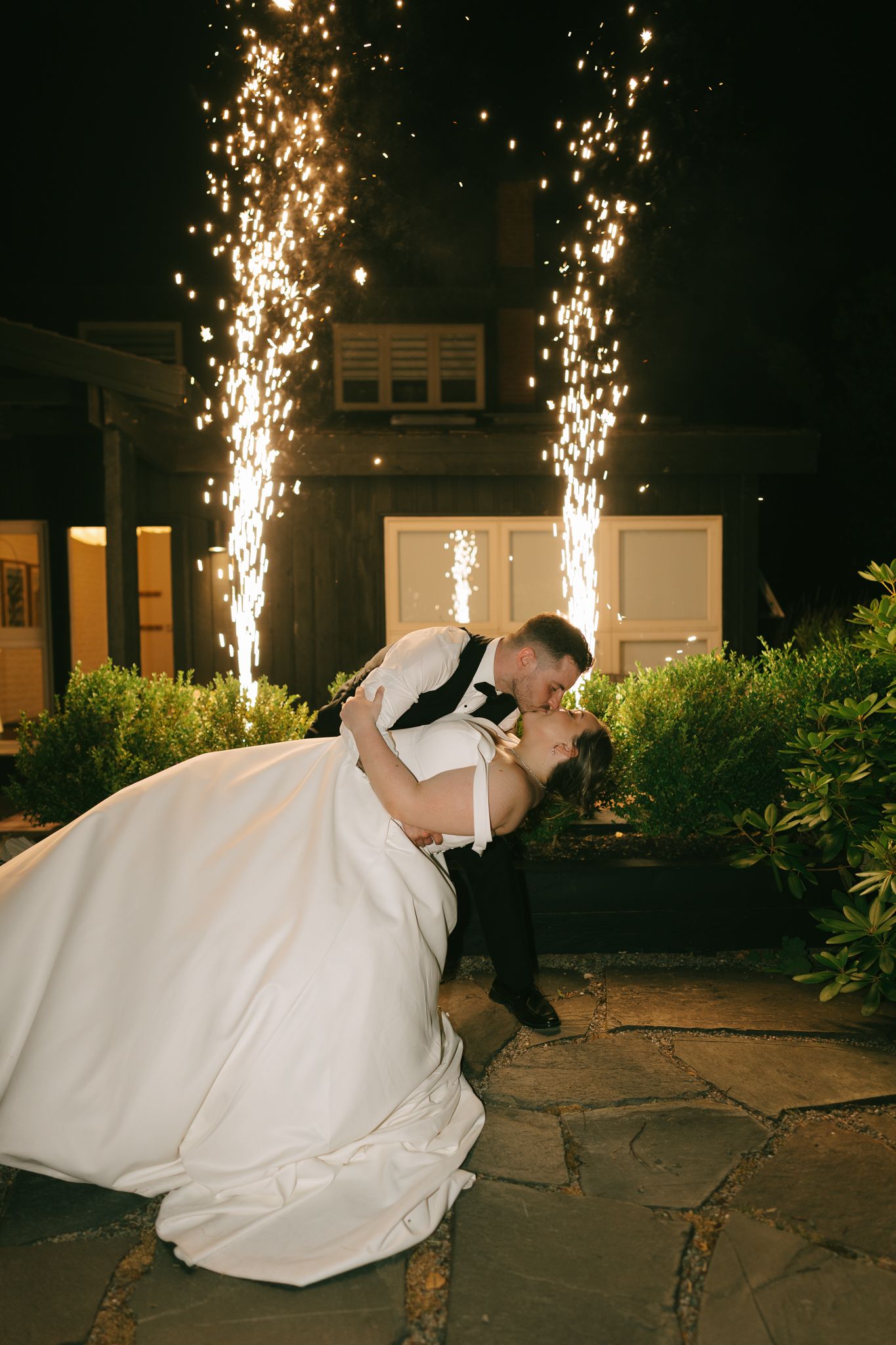 Dramatic nighttime wedding photo with sparklers creating light trails in the background.