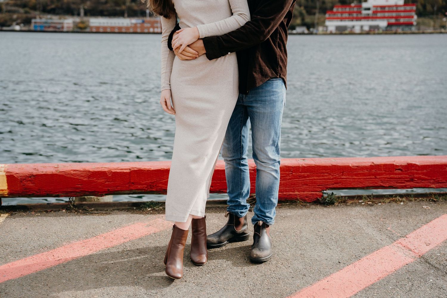 An intimate moment captured along a red-painted harbor walkway with water views.