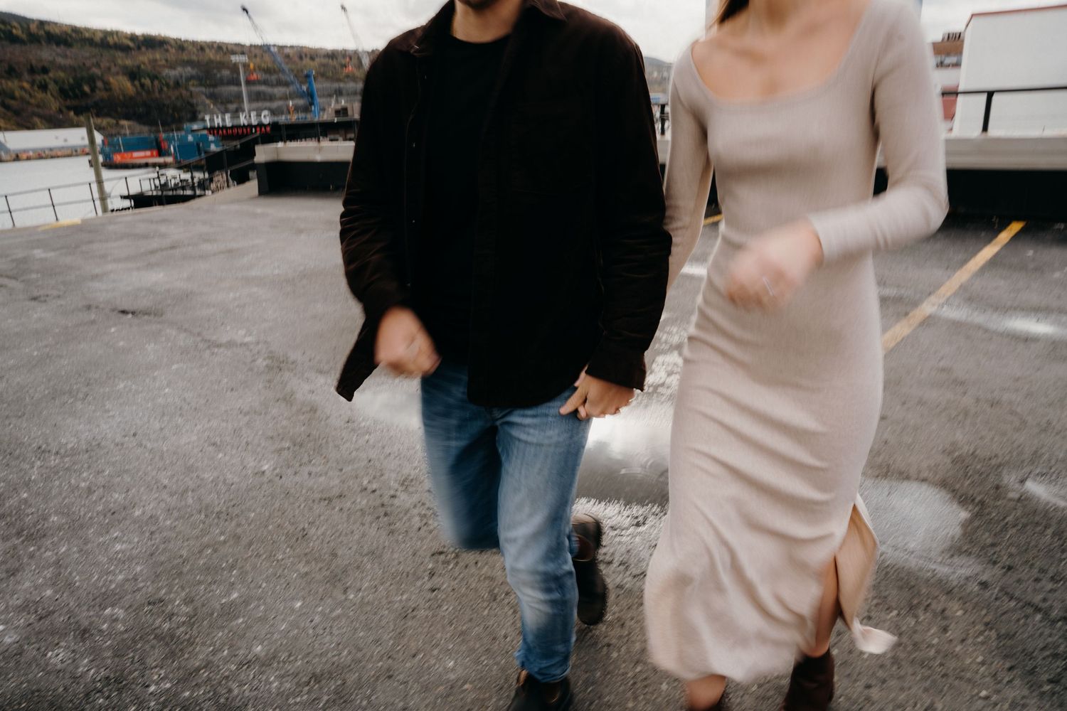 A couple in casual attire walking together on a rooftop parking area.