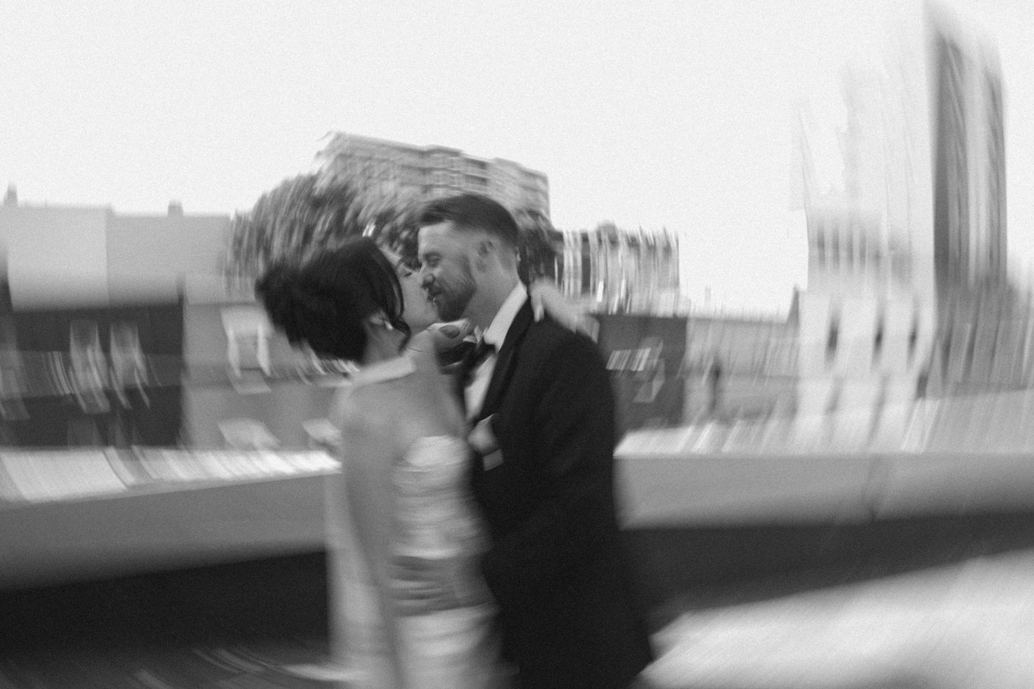 Black and white blurred photo of a couple in wedding attire sharing a romantic moment outdoors.