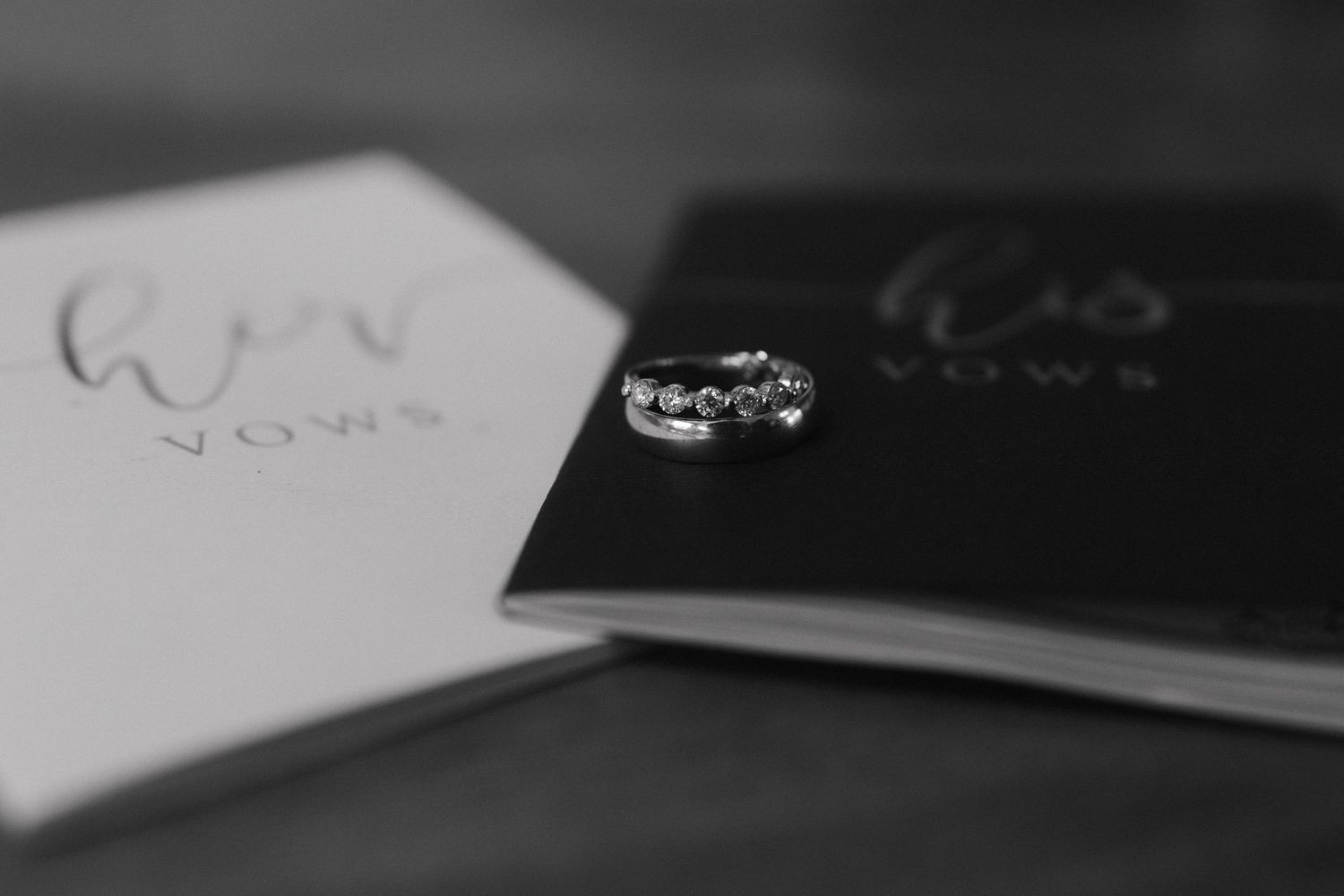 Black and white close-up photograph of a diamond ring with sparkle effect and bokeh background.