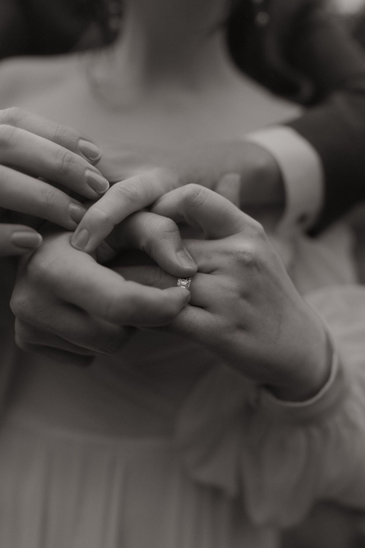 A series of black and white photos showing hands exchanging a ring during what appears to be a wedding ceremony.