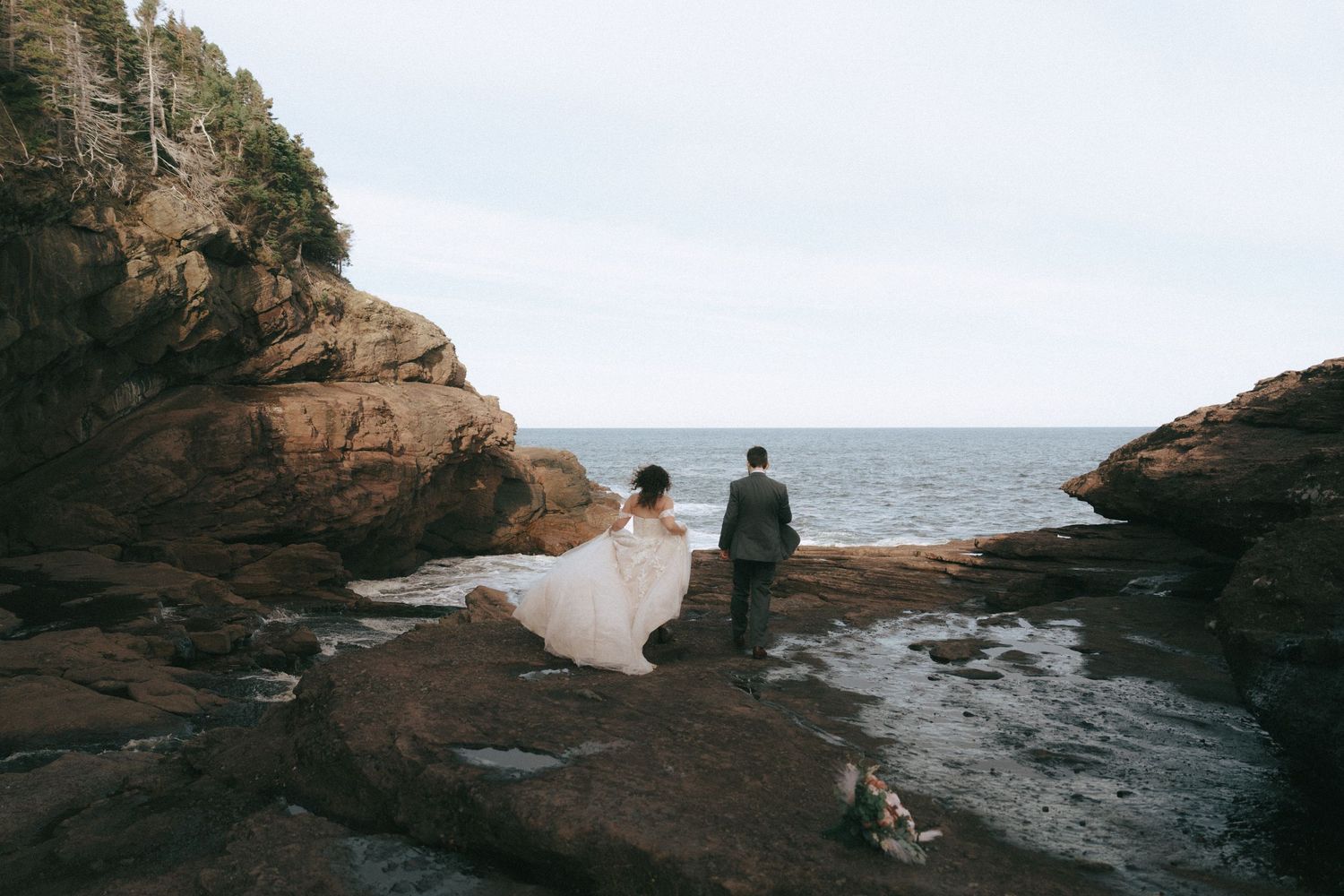 Wedding couple on dramatic rocky coastal cliffs overlooking the ocean.