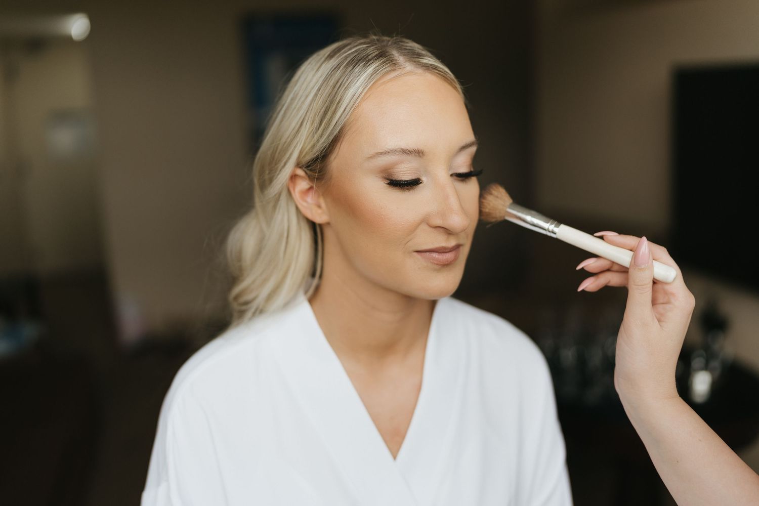 Black and white close-up shot showing makeup application during bridal preparations.
