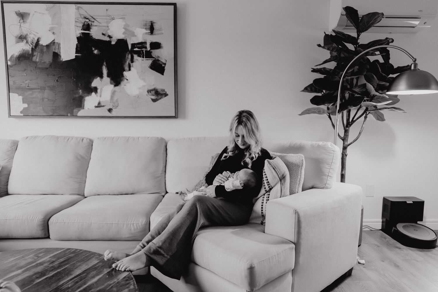 A couple shares an intimate moment on their living room couch while holding their newborn baby.