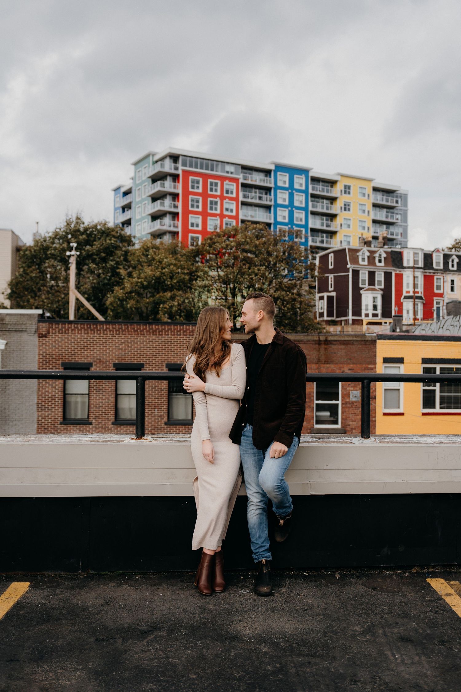 Romantic rooftop scene with modern colorful apartment complex in background.
