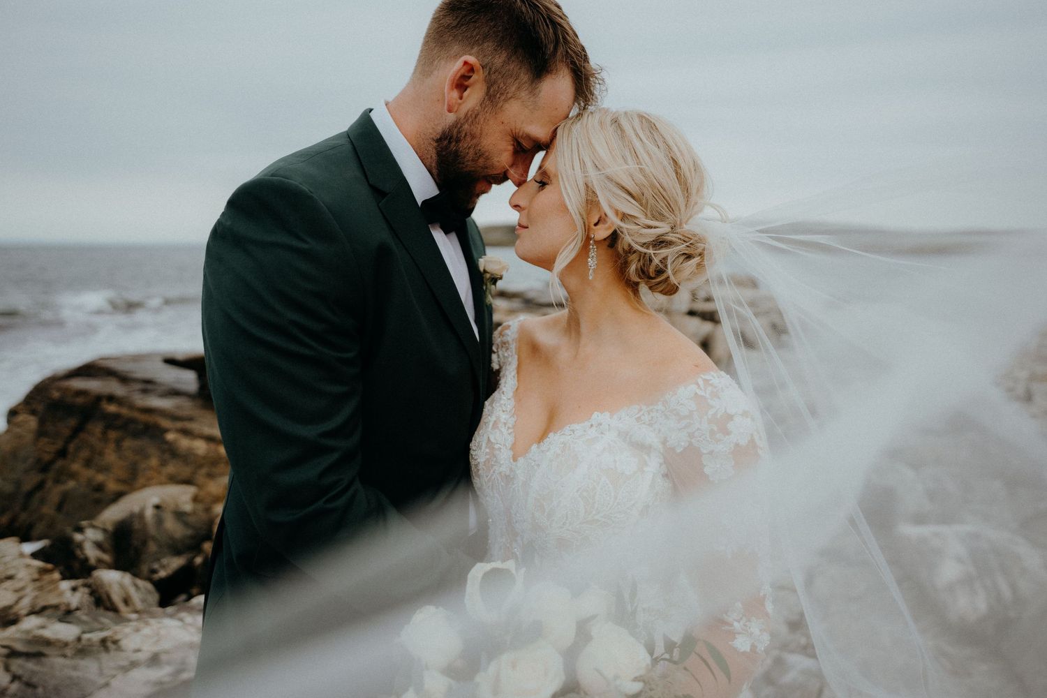 A romantic coastal portrait with waves crashing against rocky cliffs.
