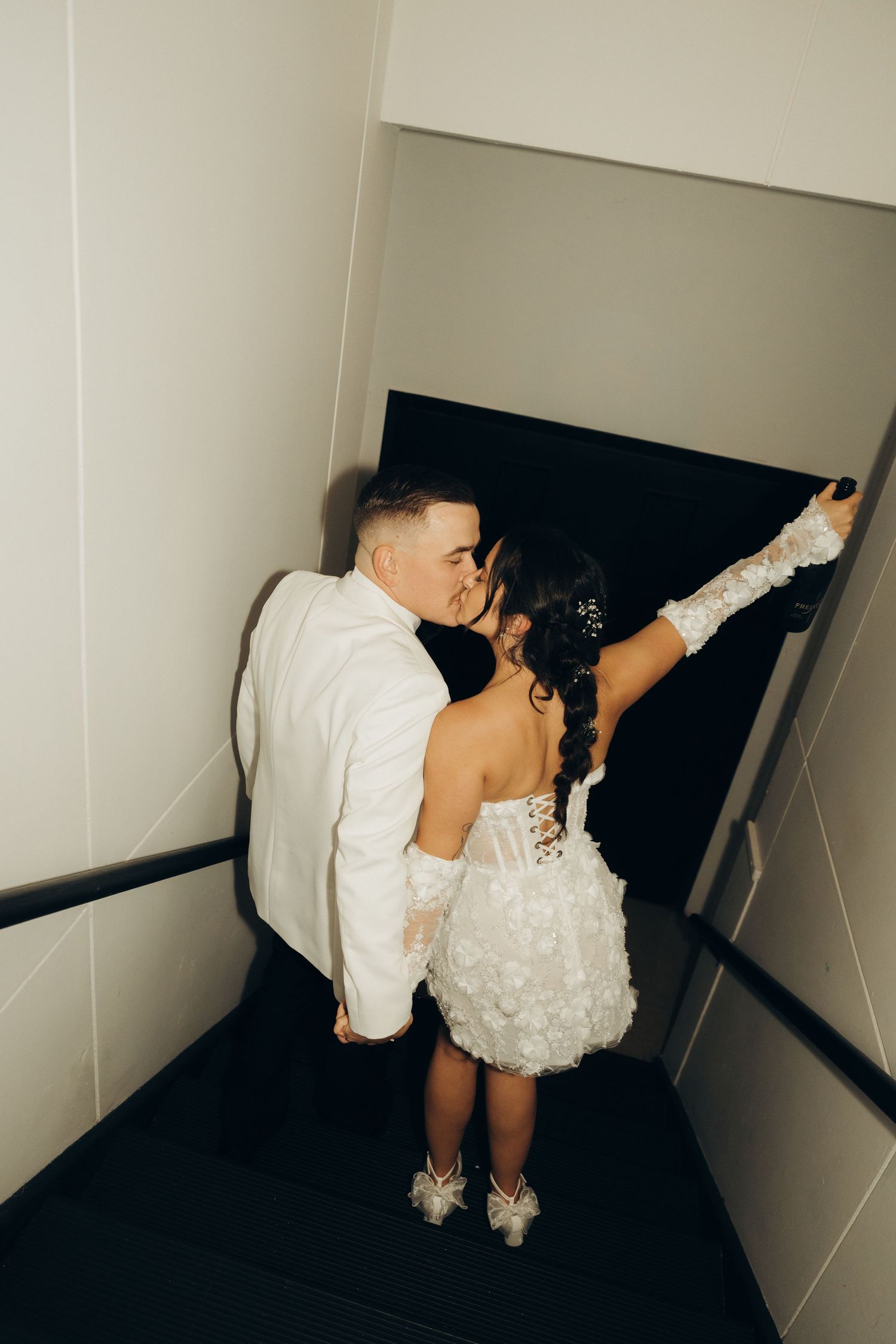 A series of four artistic black and white photos showing a couple in wedding attire dipping in a minimalist hallway setting.