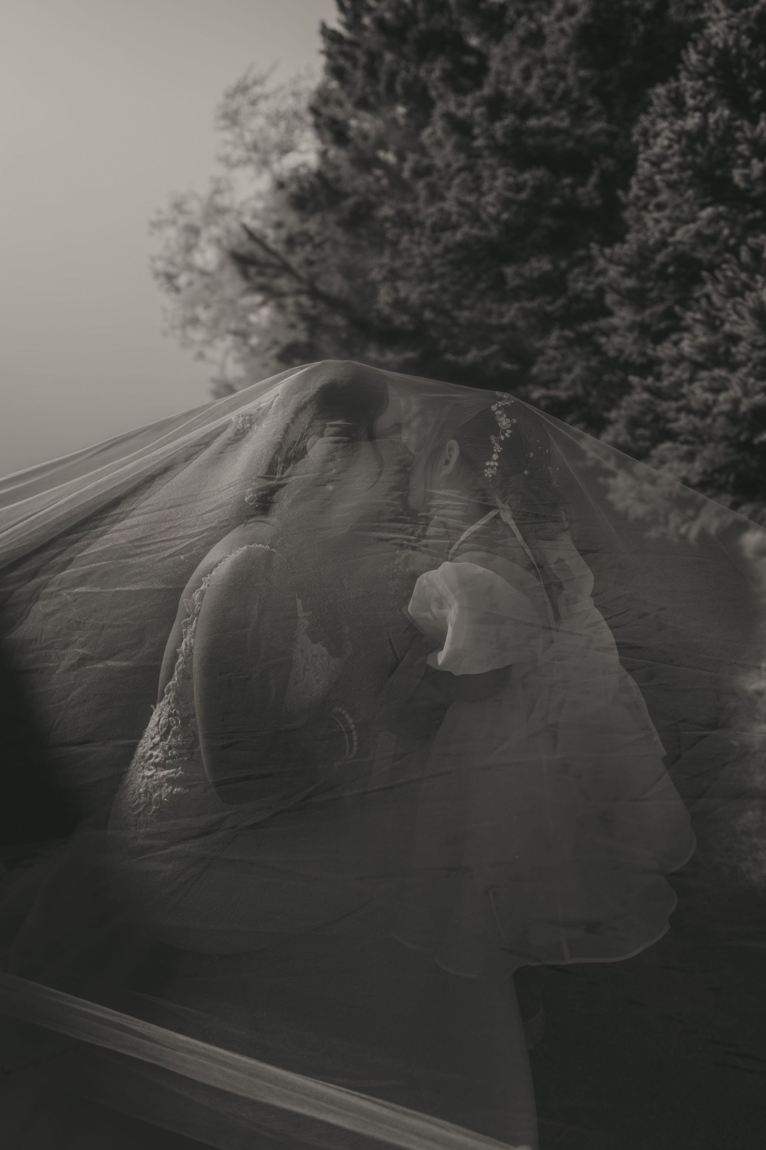 Multiple exposure black and white photograph shows ghostly silhouettes overlapping against a blurred outdoor background.