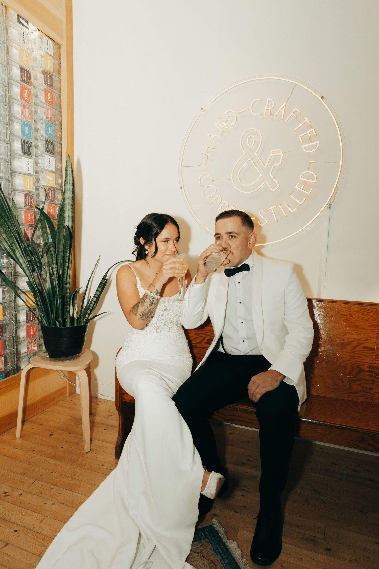 A couple in wedding attire shares intimate moments in a minimalist indoor setting with white walls and wooden floors.