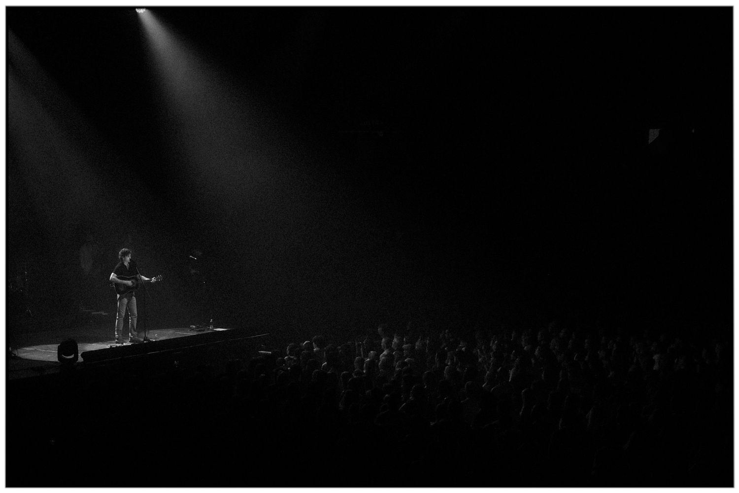 Dark silhouettes of performers on stage during a dramatic concert with moody lighting and atmospheric effects.