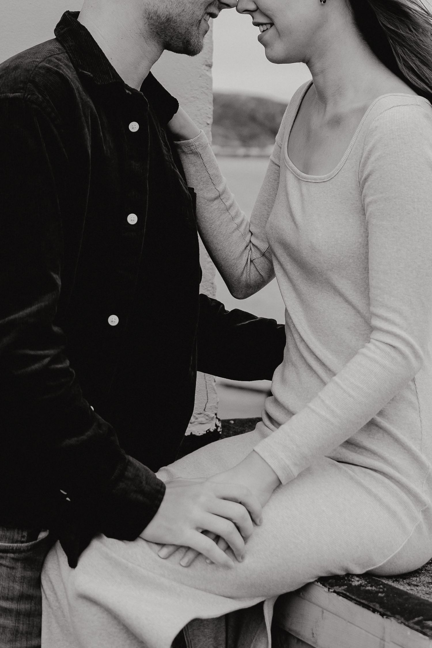 An intimate couple embracing in black and white photography by the ocean.