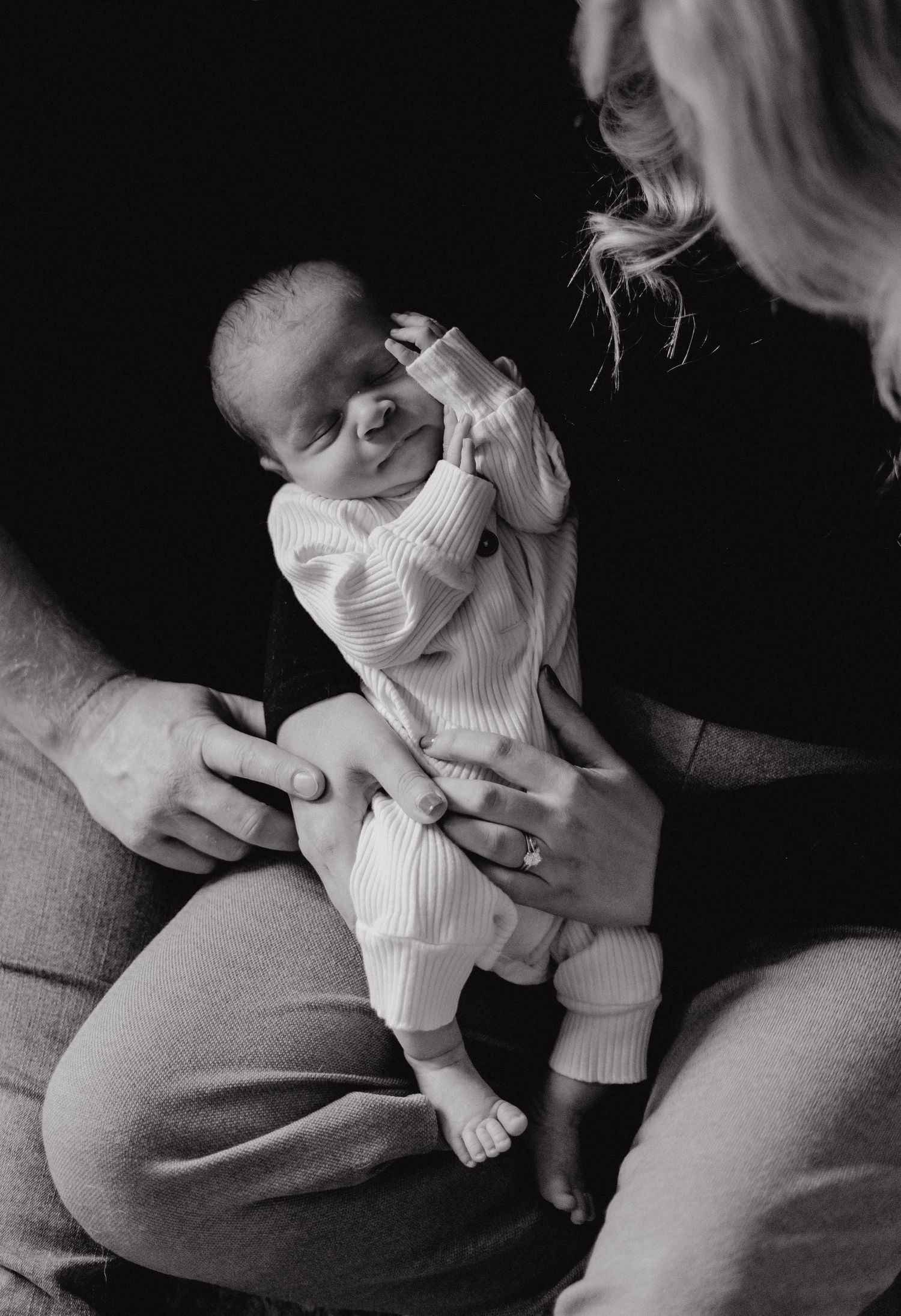 Intimate photography session of a baby in white clothing on a textured surface.