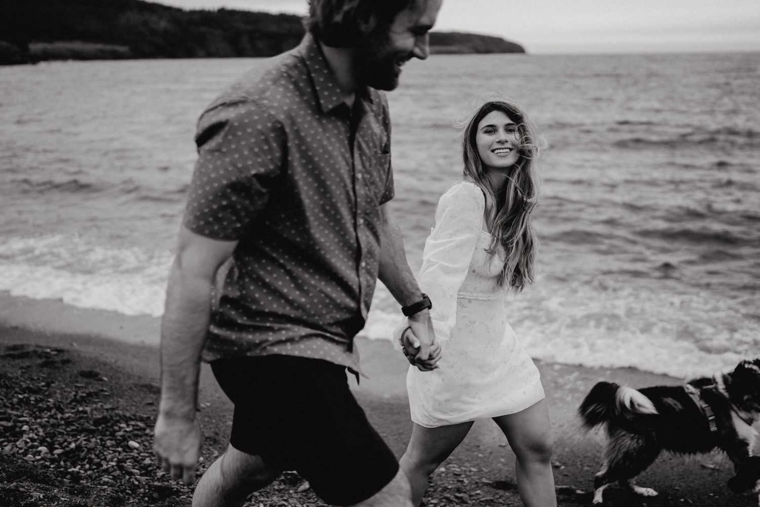 A pair explores the scenic rocky shoreline together during an outdoor photo session.