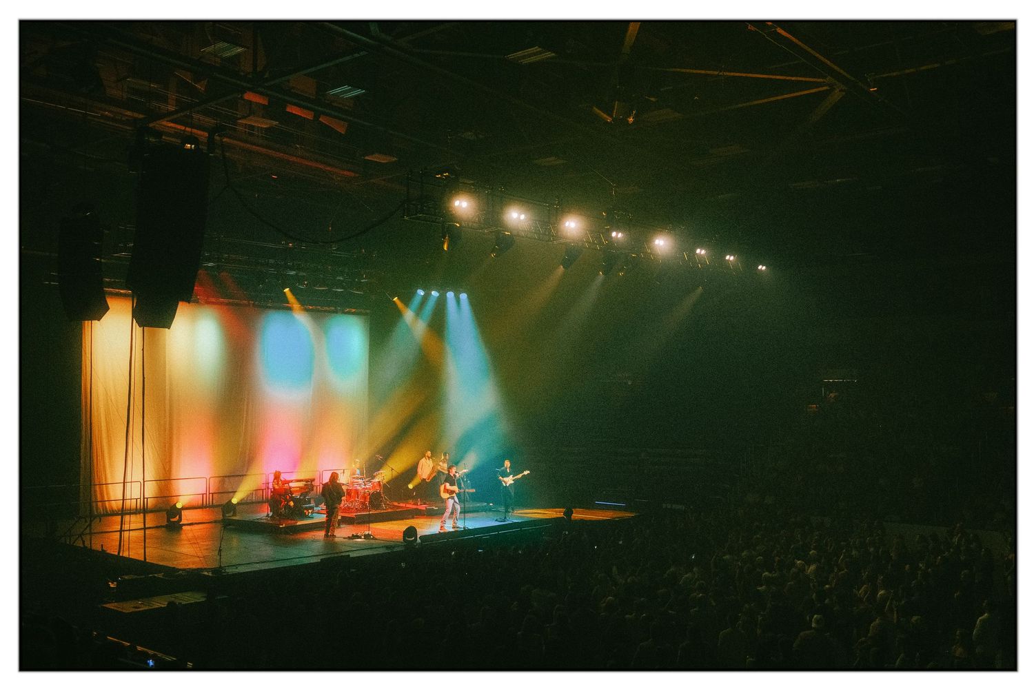 Concert stage bathed in warm orange and blue lighting with atmospheric fog effects creating a moody ambiance.