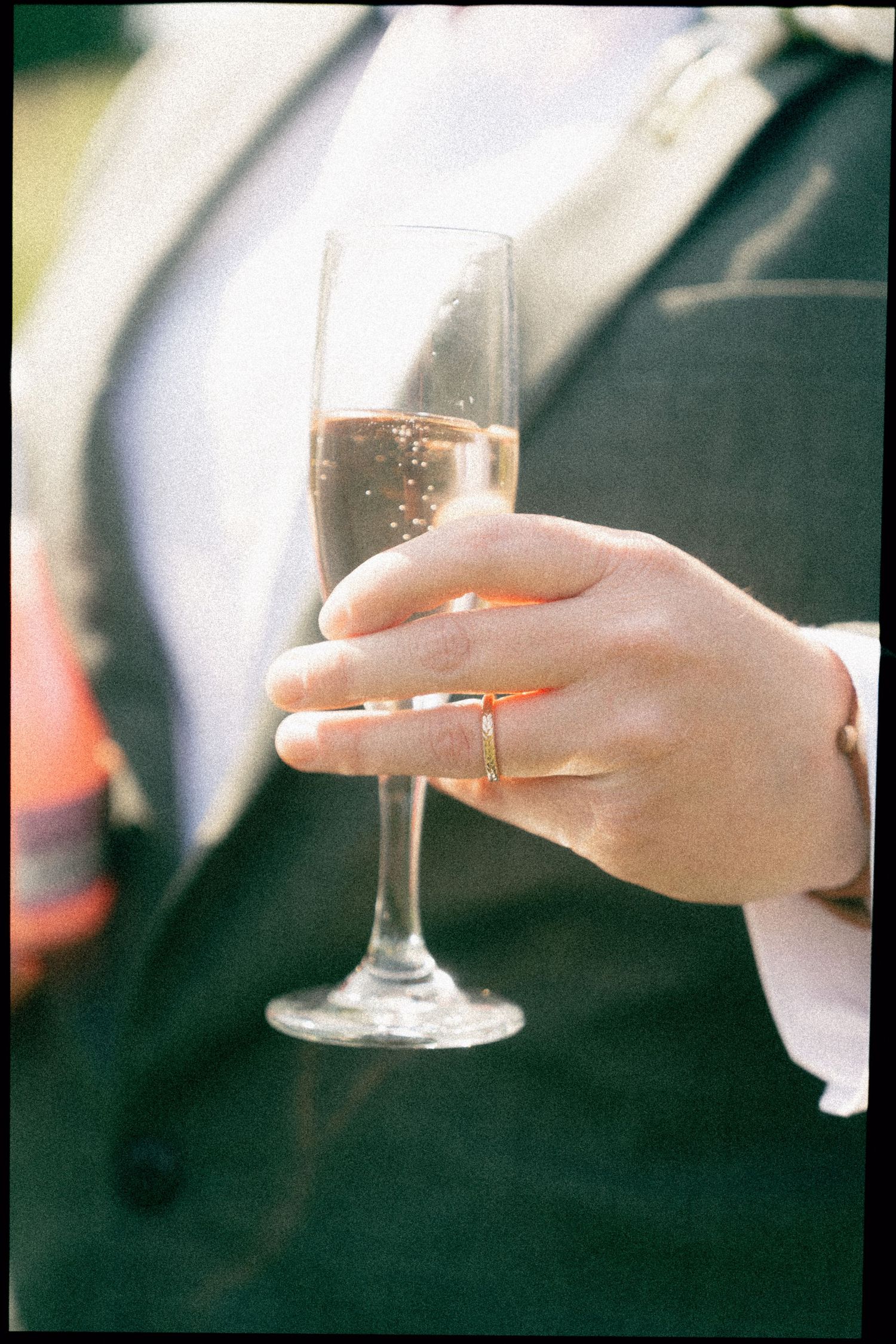 Close-up shot of hands holding champagne glasses during an outdoor celebration.