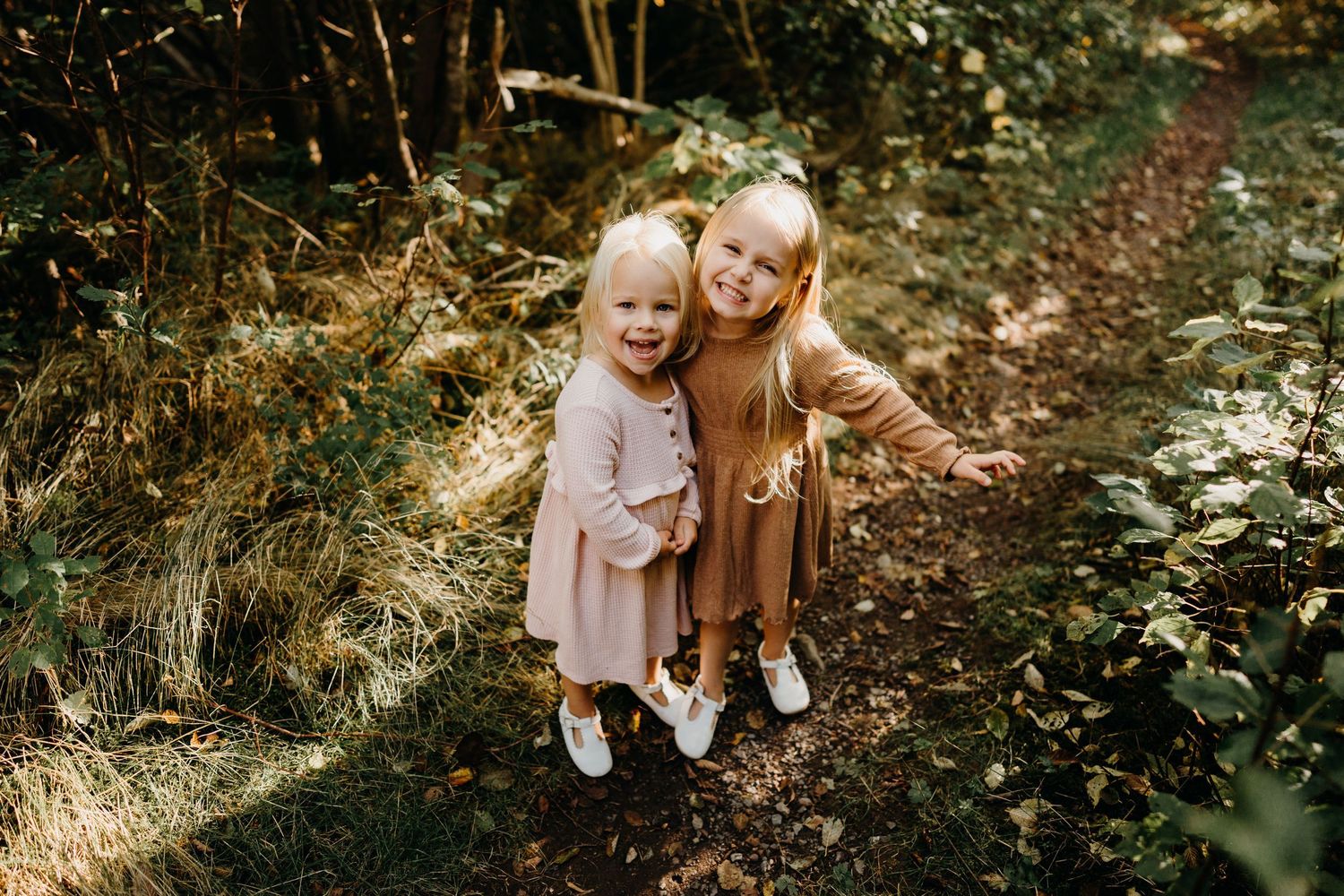 Candid family interactions photographed in dappled sunlight through forest trees.