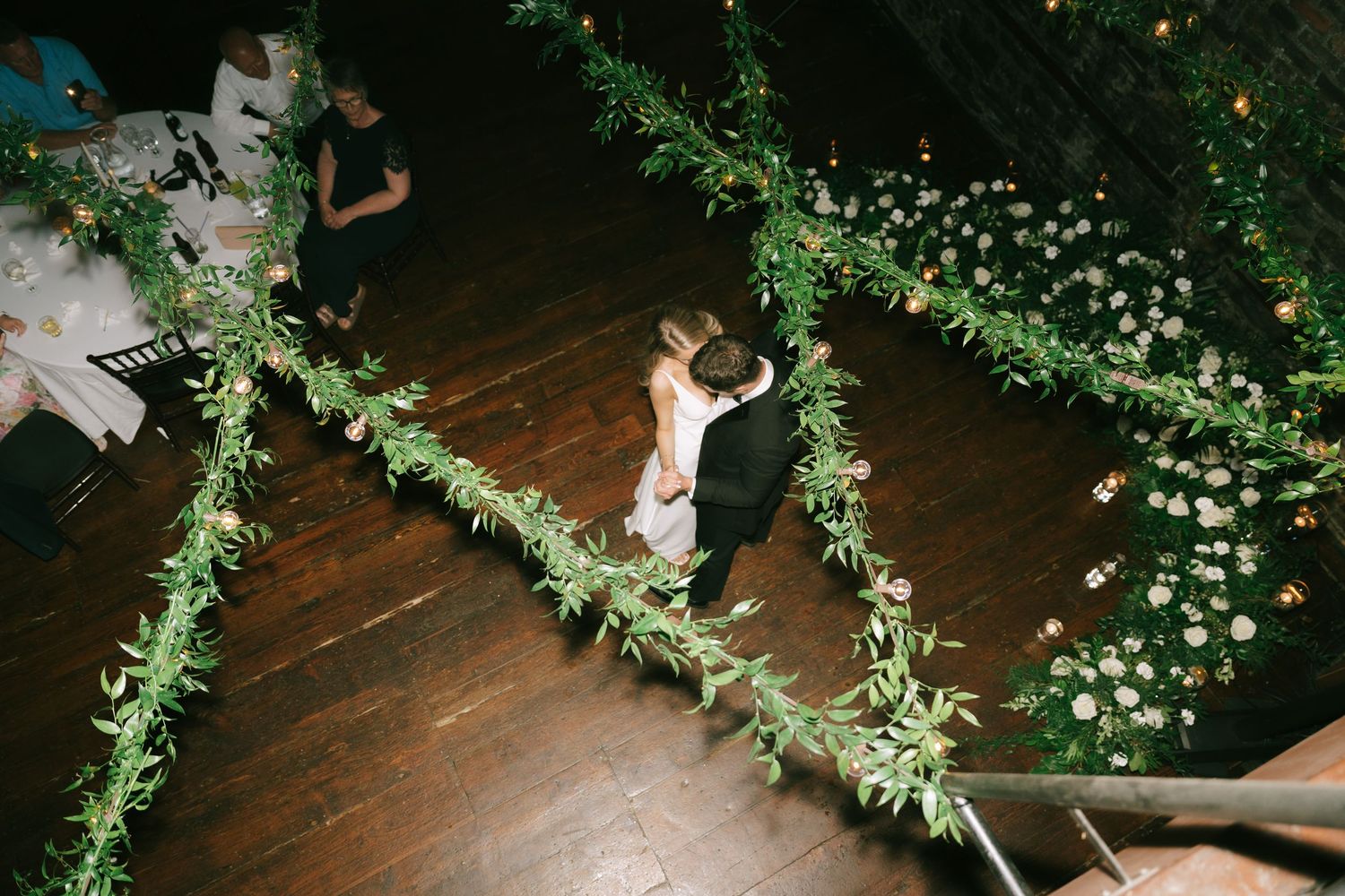 Elegant wedding reception venue with hanging greenery and string light decorations.