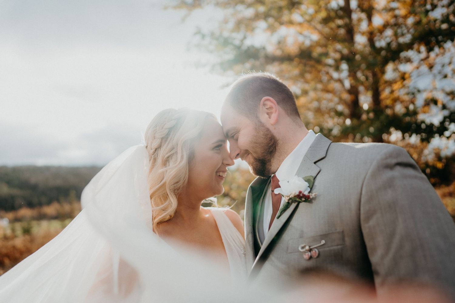 A romantic autumn wedding scene with golden sunlight filtering through trees.
