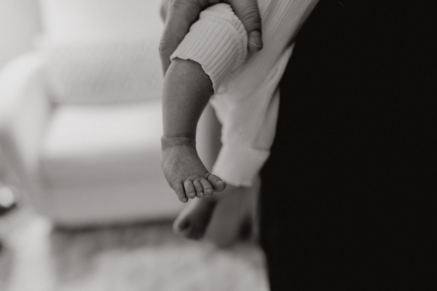 Loving embrace between adults with baby in modern nursery setting.