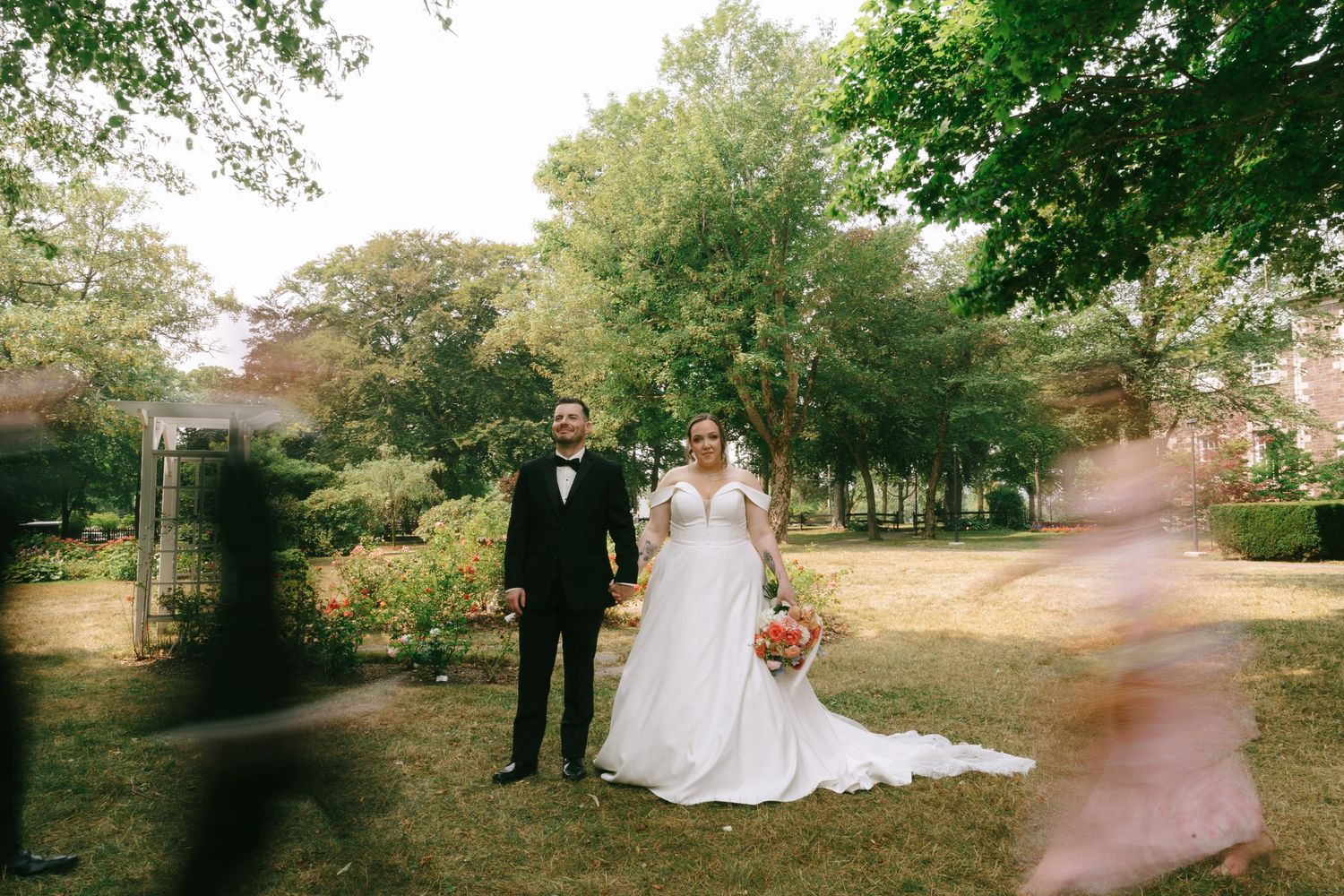 Wedding party members walk on a tree-lined path during an outdoor photo session.