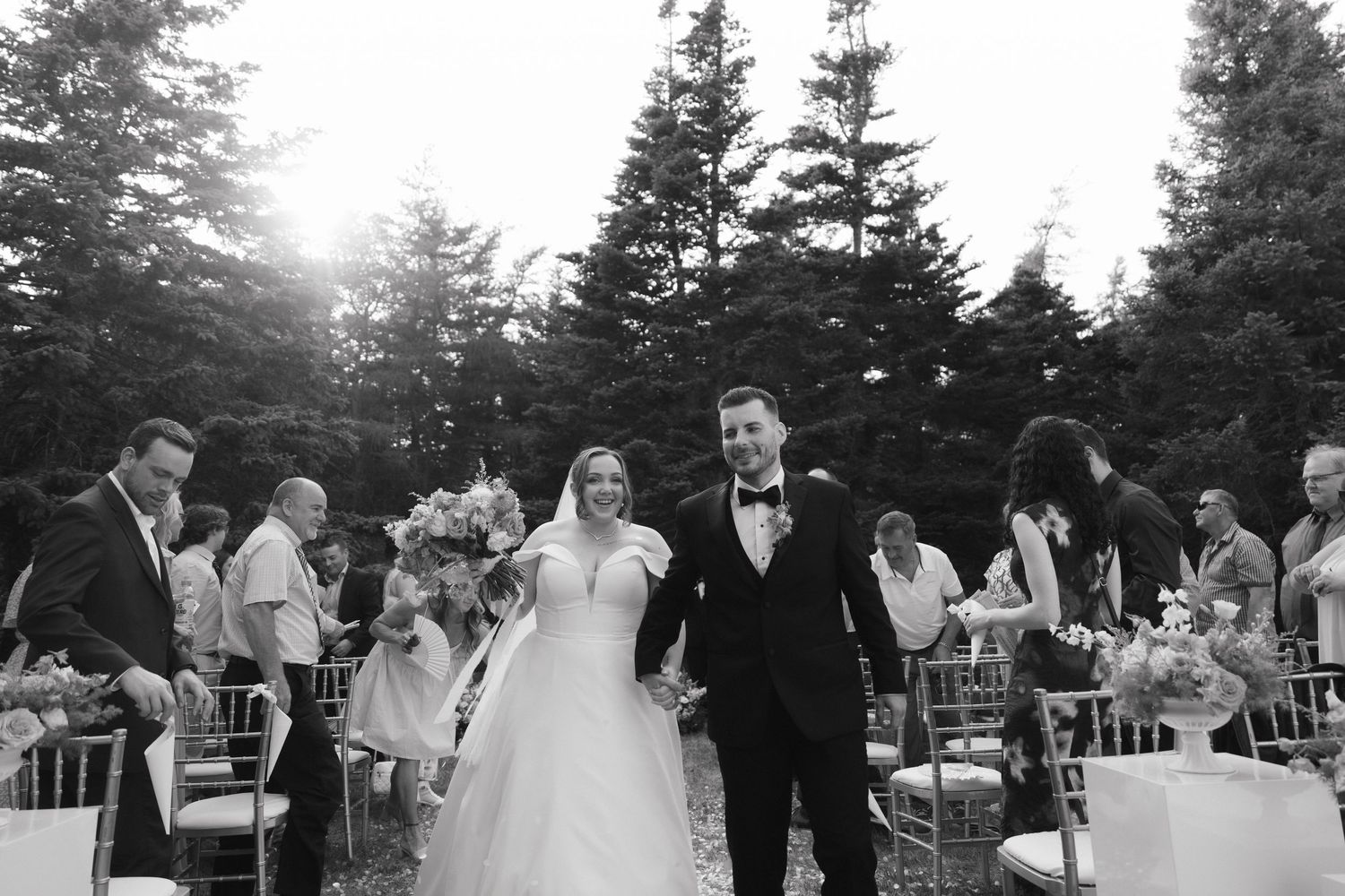 Outdoor wedding celebration against a backdrop of tall pine trees.