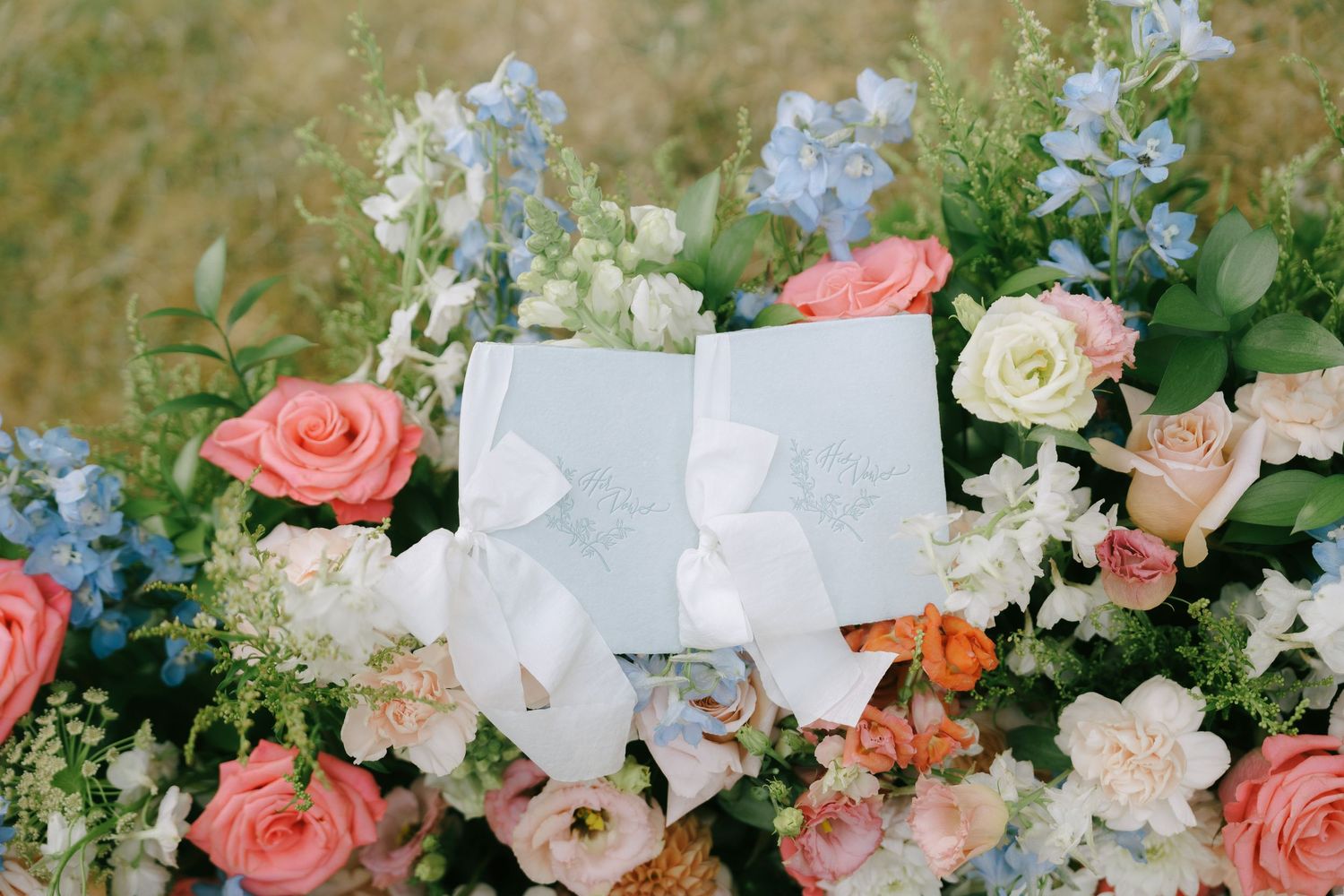 Delicate floral arrangements featuring coral roses, white orchids, and greenery create an elegant wedding decor display.