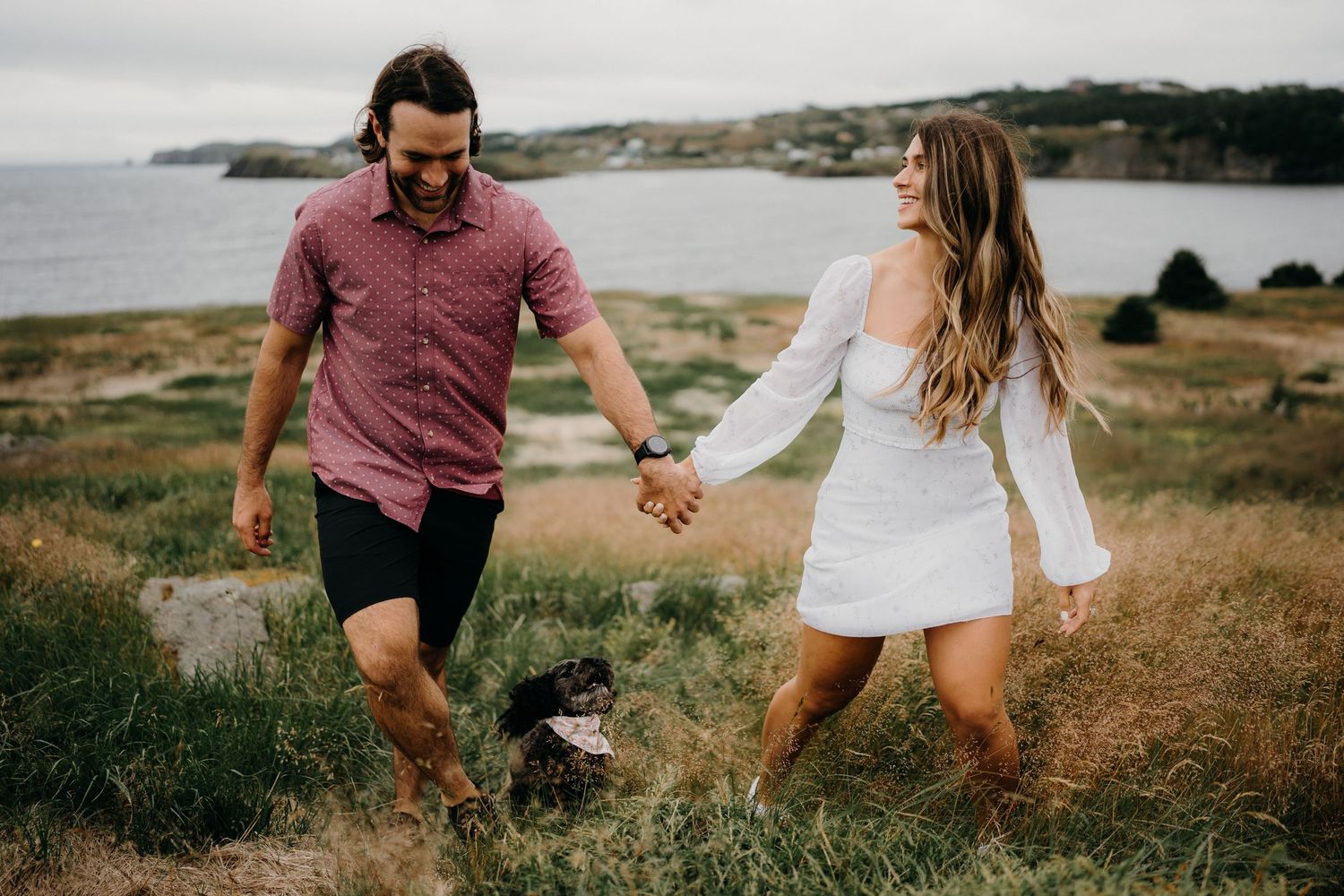 Couple walking together on a scenic coastal trail with ocean views.