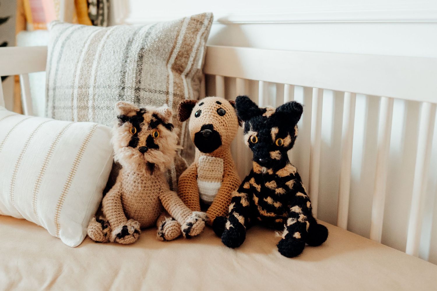 White crib with plush stuffed animals lined up against the railing in a nursery.