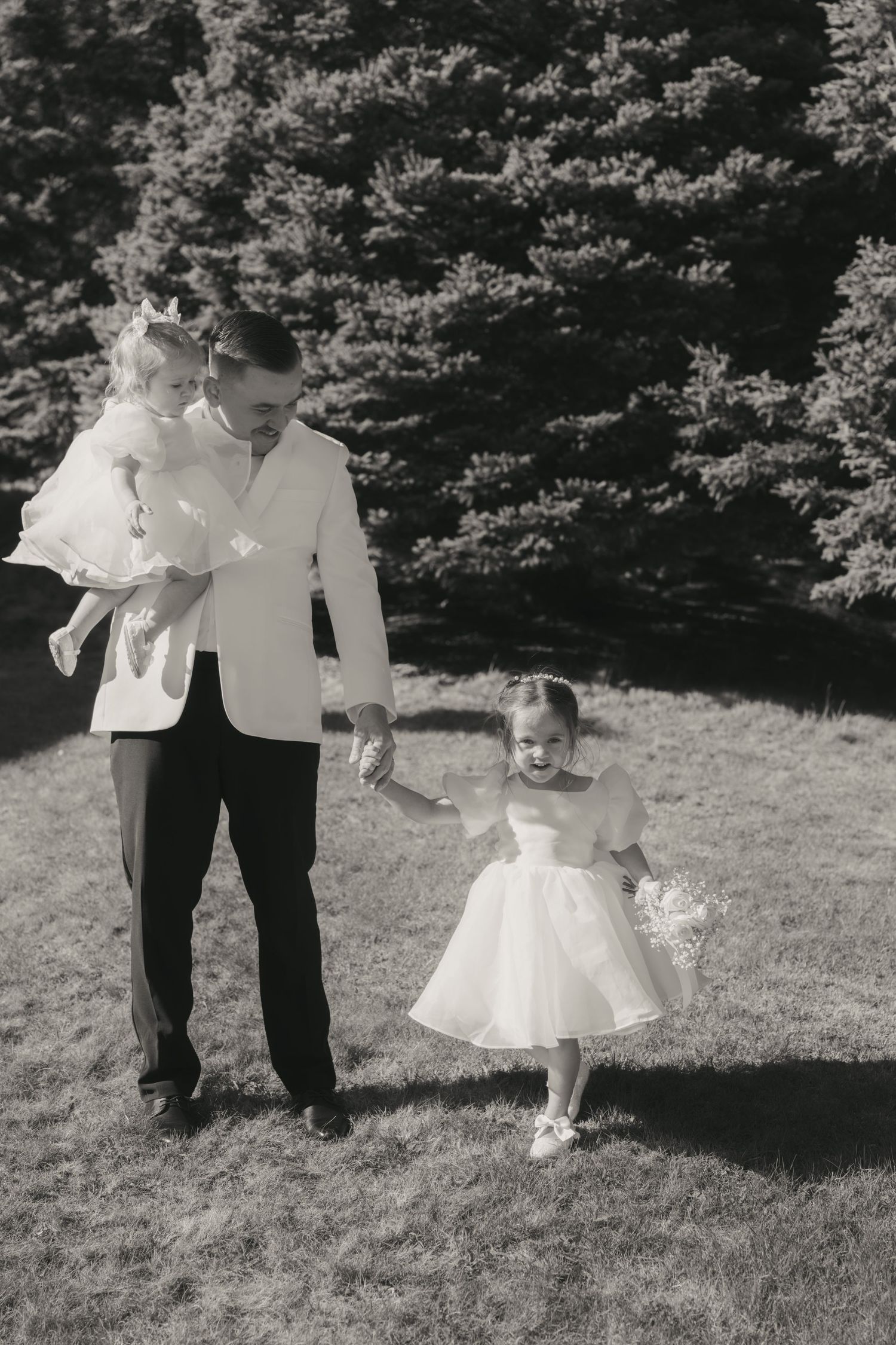 Black and white photos show a small child in a white dress walking on grass with an adult figure nearby.
