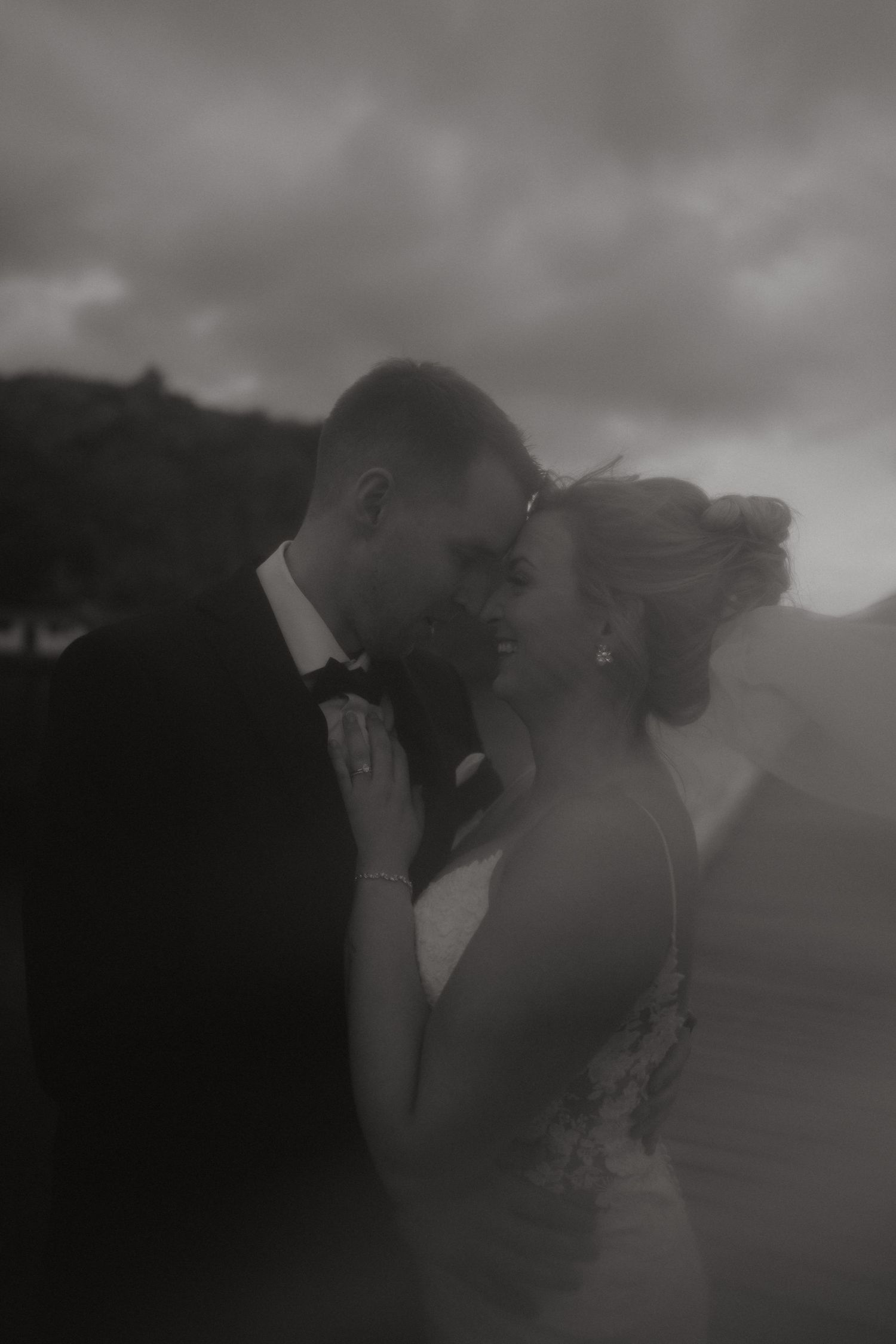 Moody black and white wedding portraits captured on a cloudy day by the ocean.
