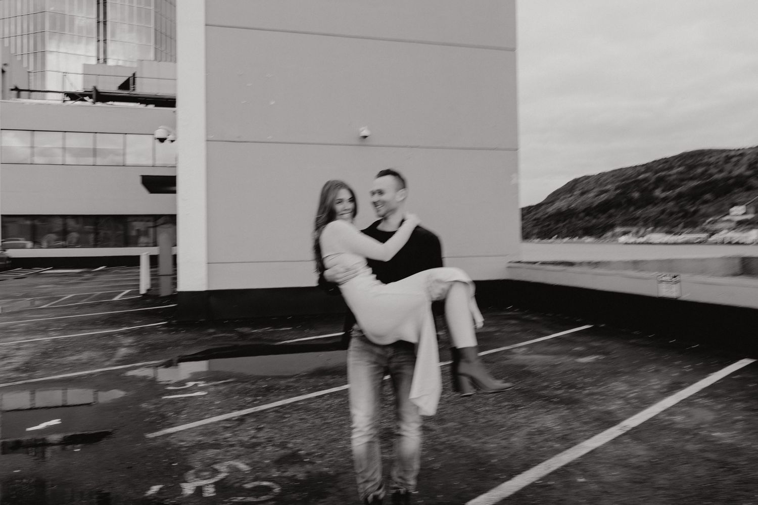 Black and white image of couple sharing tender moments against a white wall background.