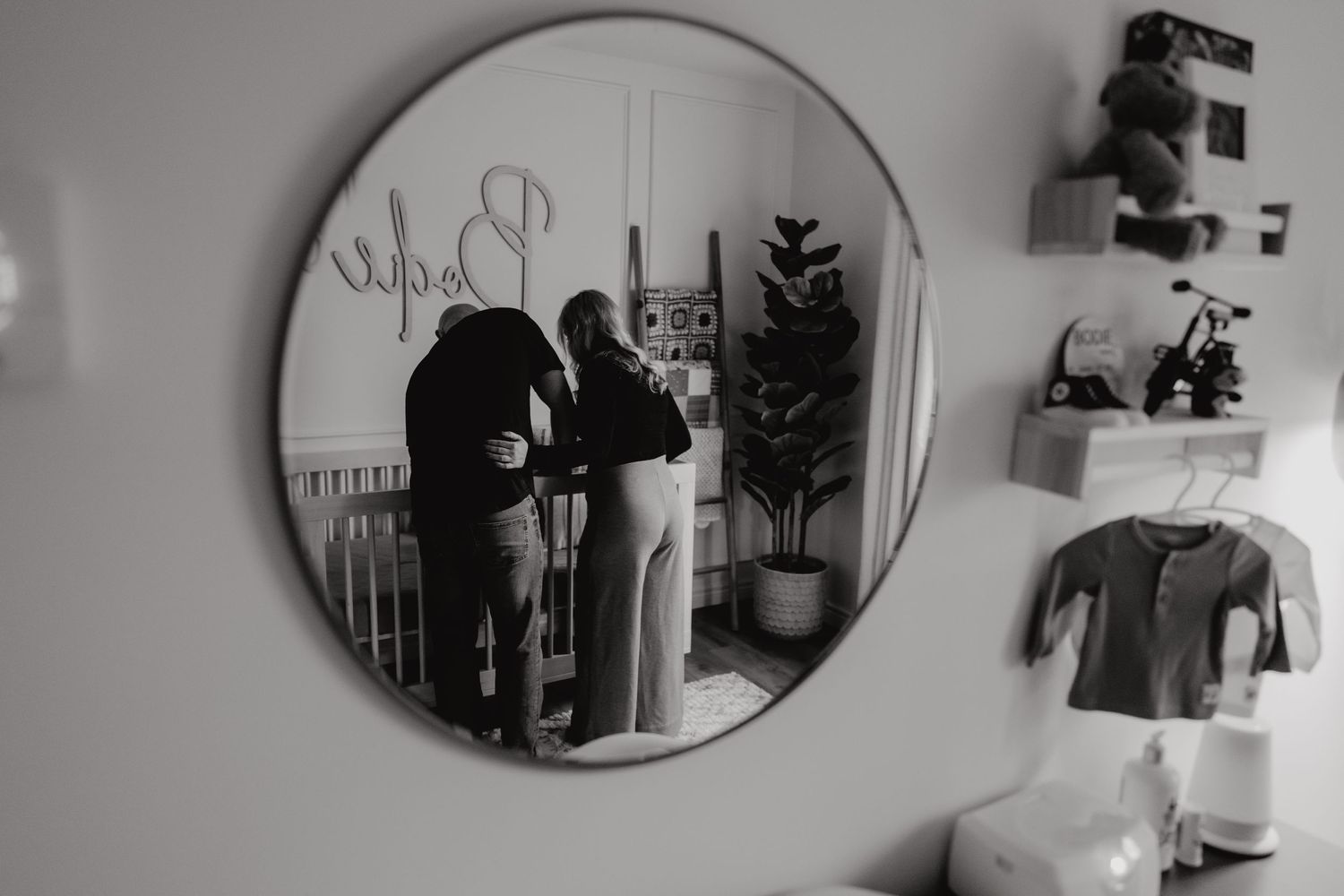 Round decorative mirror on wall reflecting nursery room decor.