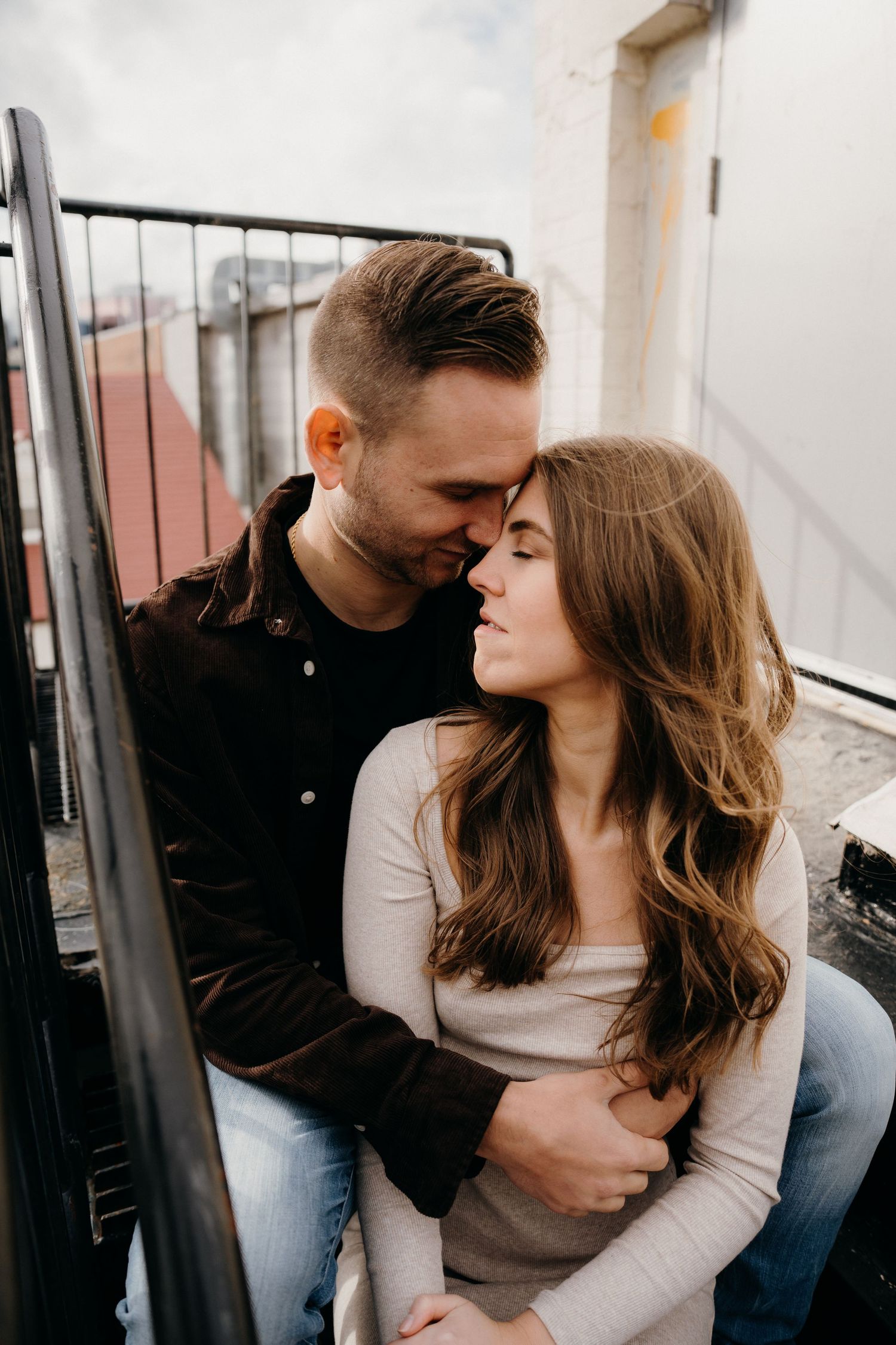 Candid moments between couple during rooftop photoshoot in natural lighting.