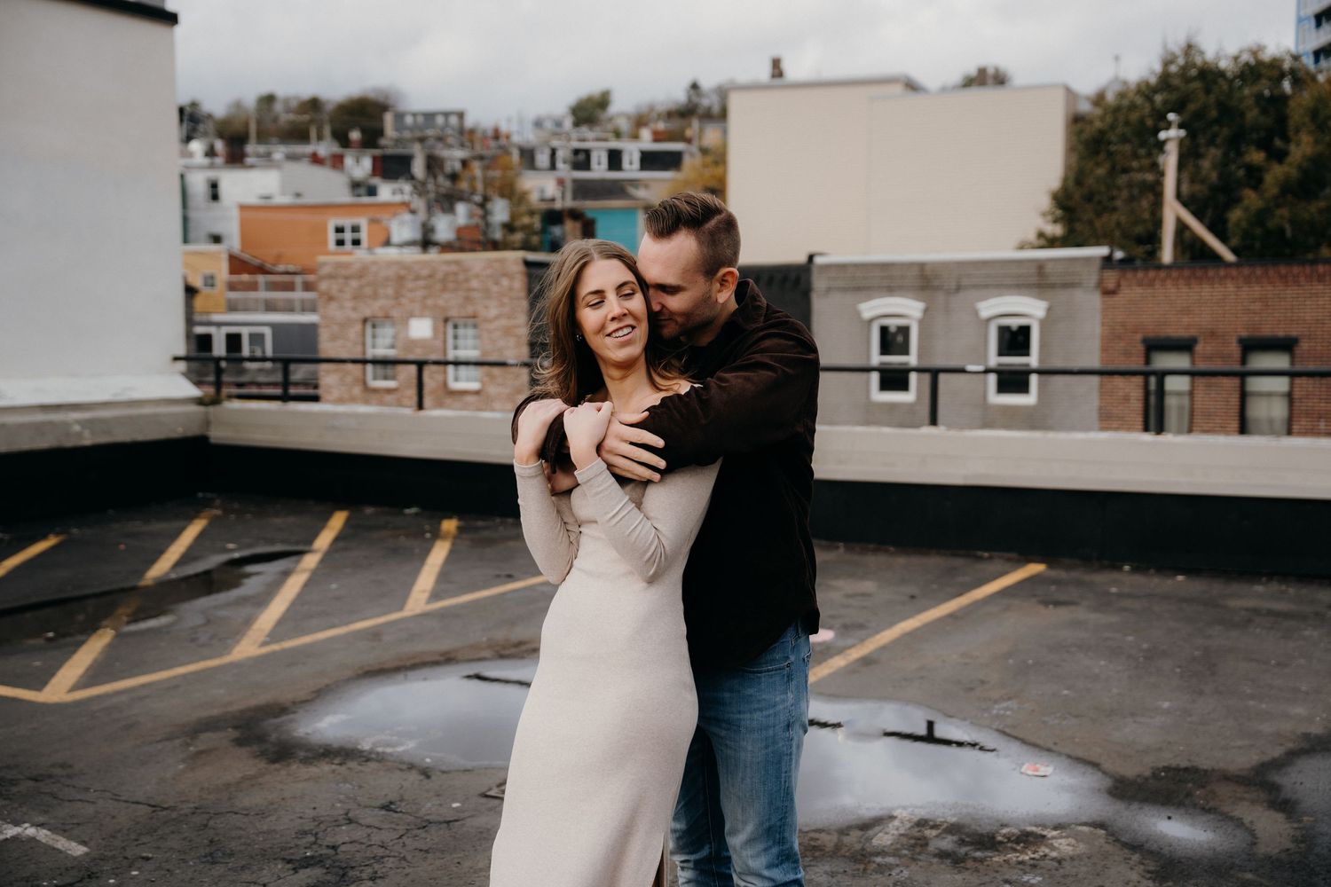 Intimate couple shares tender moment on empty city rooftop during monochrome photoshoot.