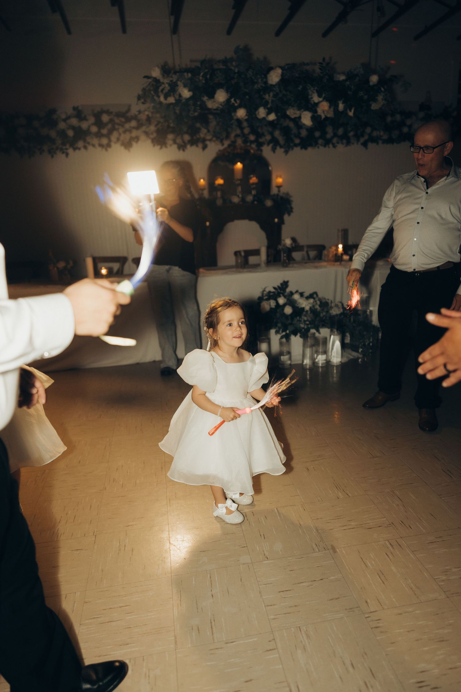 A sequence of dance floor photos shows someone in a white dress twirling with sparklers at a wedding reception.