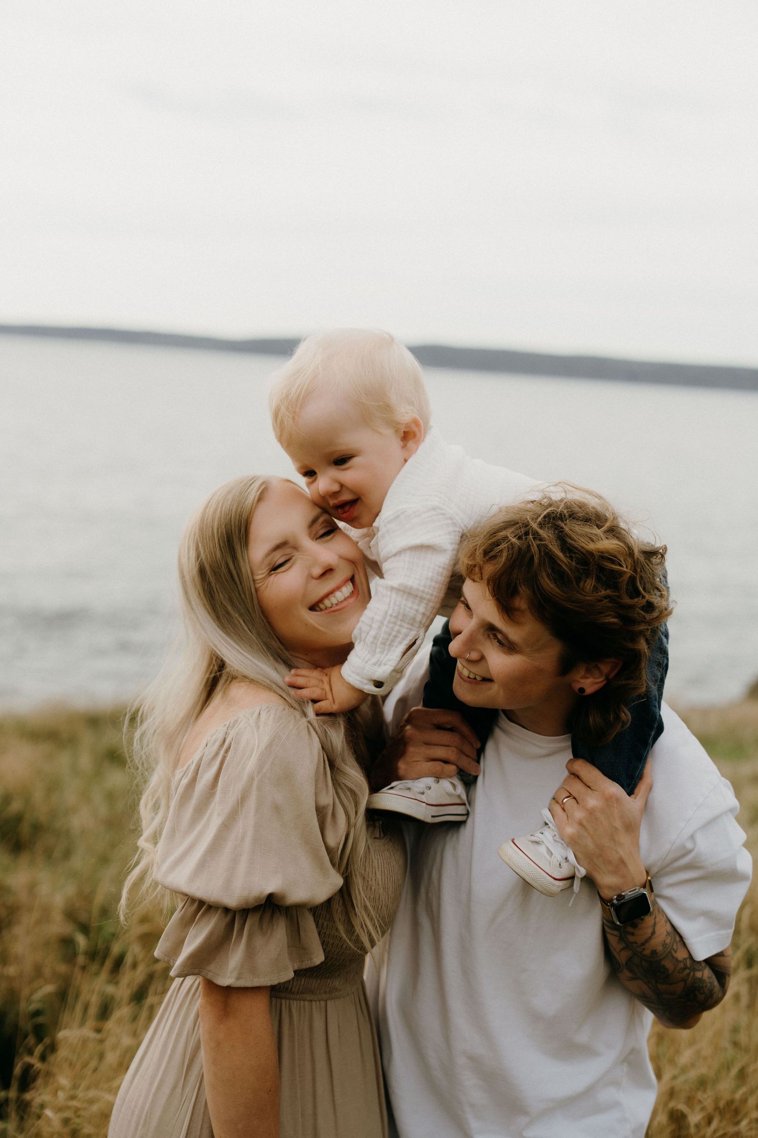 A couple shares intimate moments of laughter and affection in a series of candid photos by the ocean.